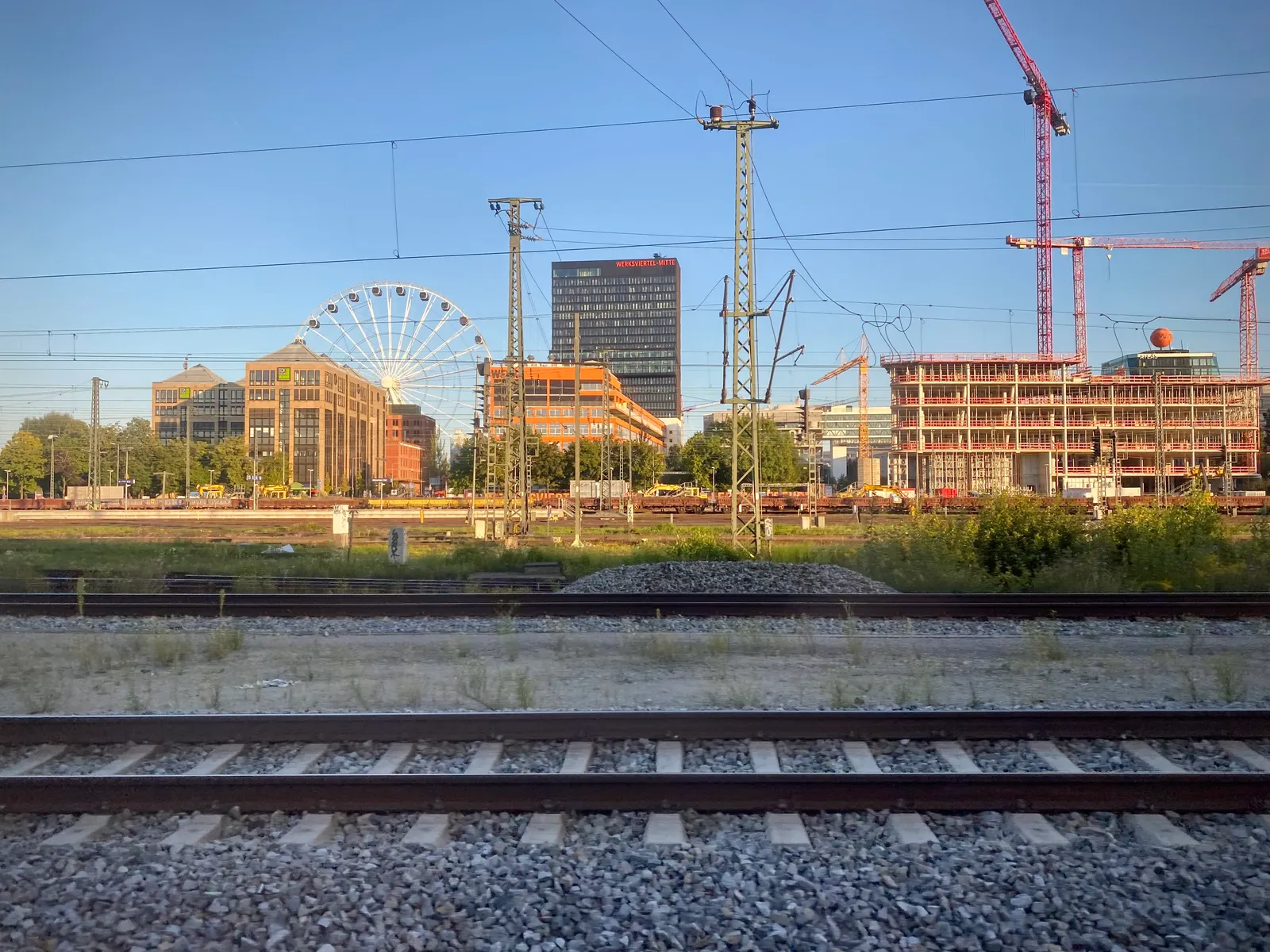 The Werksviertel skyline seen across the rail tracks from Munich Ostbahnhof, the Ferris wheel and converted factory buildings mixed in with active construction cranes