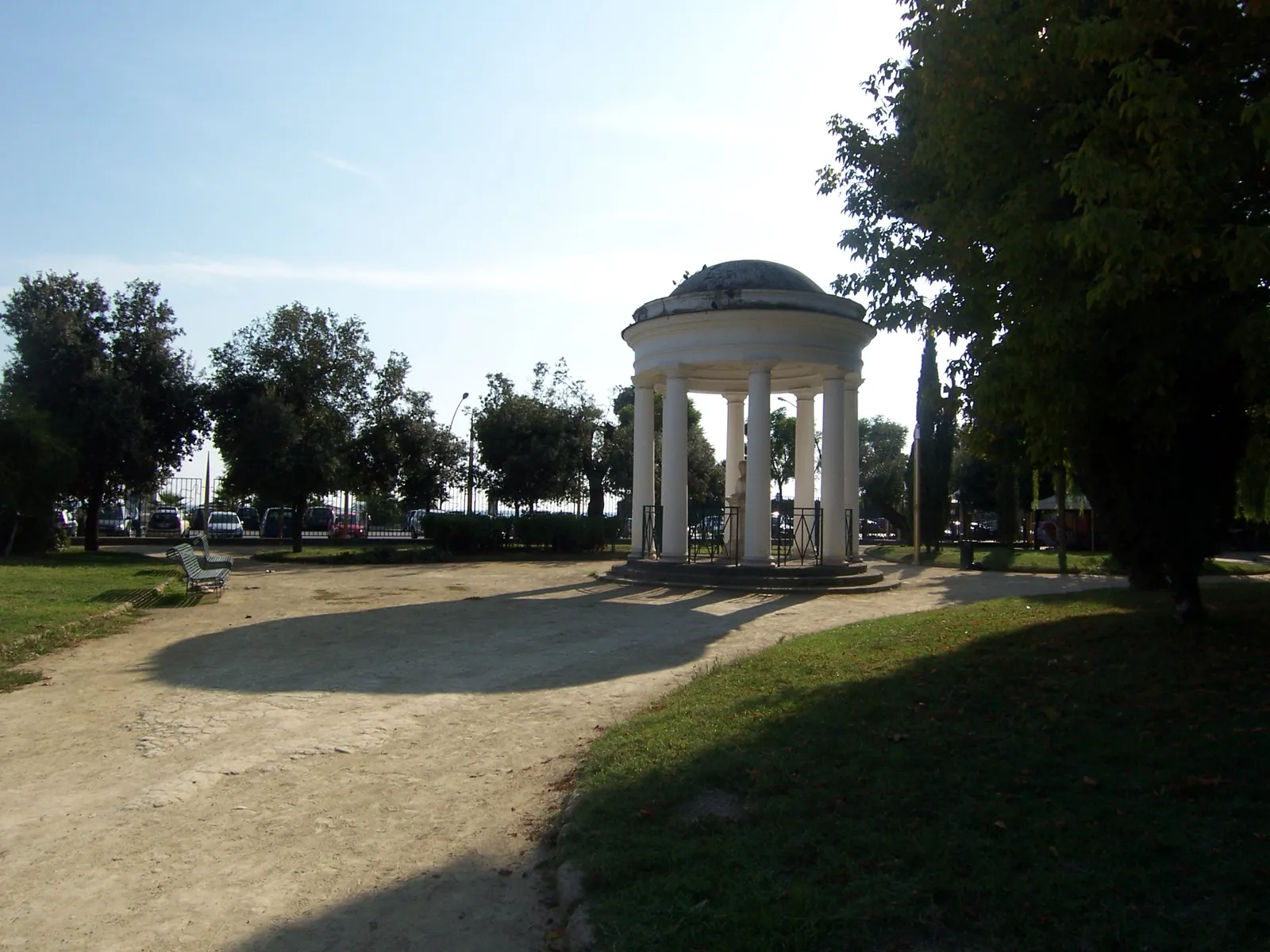 The Cassa Armonica bandstand in the Villa Comunale in Naples, a circular white pavilion with cast-iron columns and a glass dome, on a gravel path among trees
