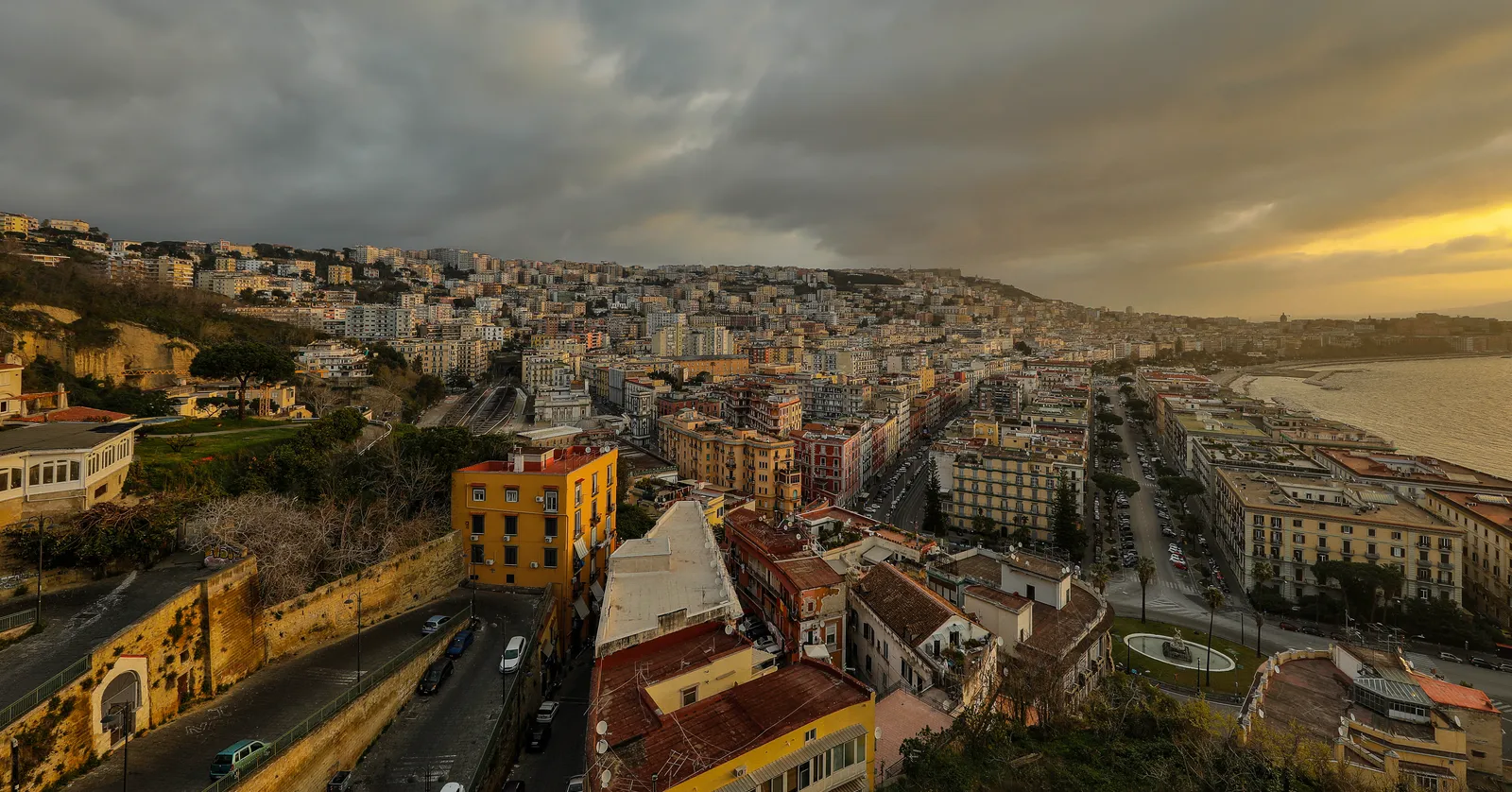 Naples seen at sunset from the Posillipo ridge, looking down over the packed rooftops of Mergellina and along the curve of the seafront to the bay