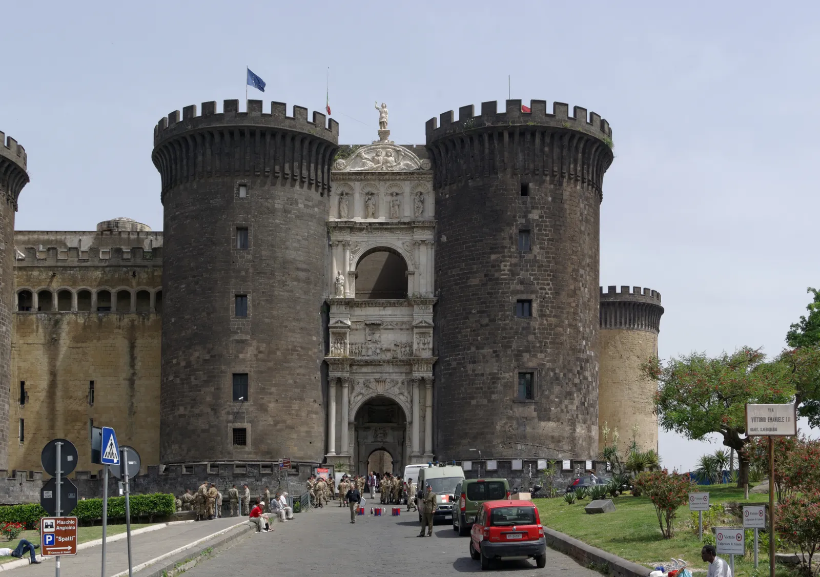 Castel Nuovo in Naples, a squat grey stone castle with five round crenellated towers and a tall white marble arch set into the gateway between two of them