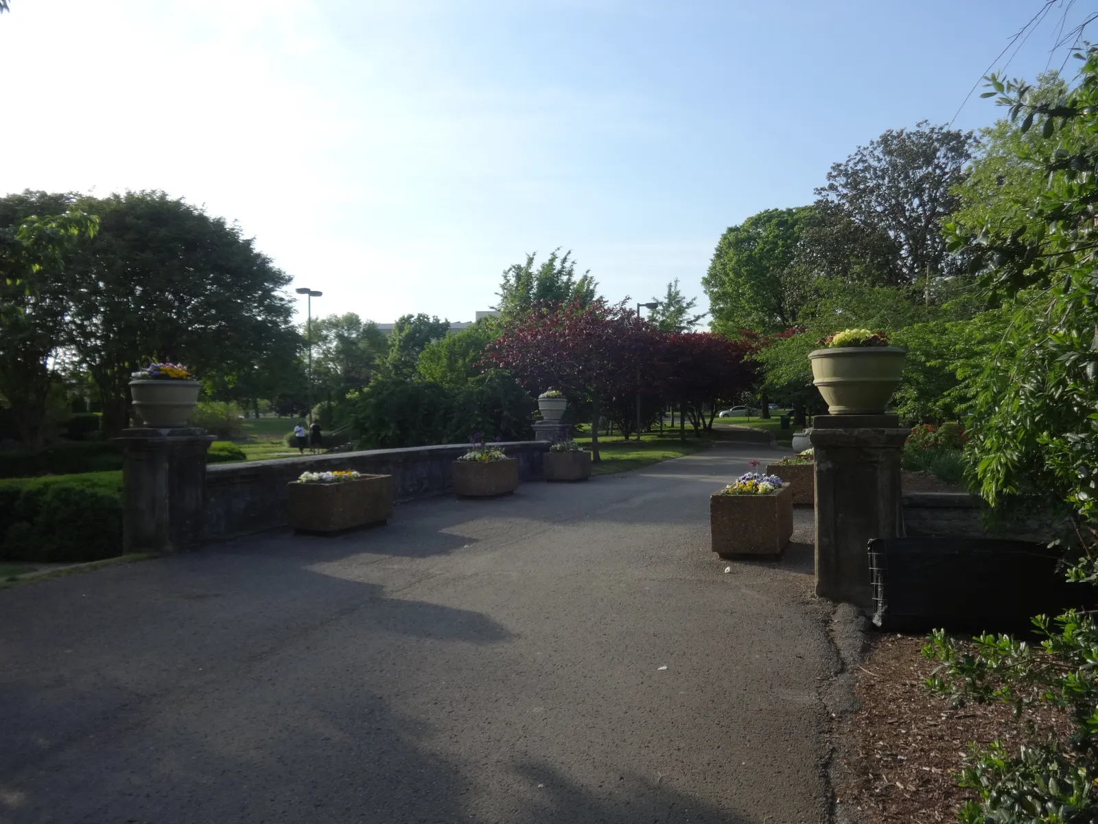 A paved path in Centennial Park, Nashville, running past a low stone balustrade topped with carved urns, with planted beds and trees beyond
