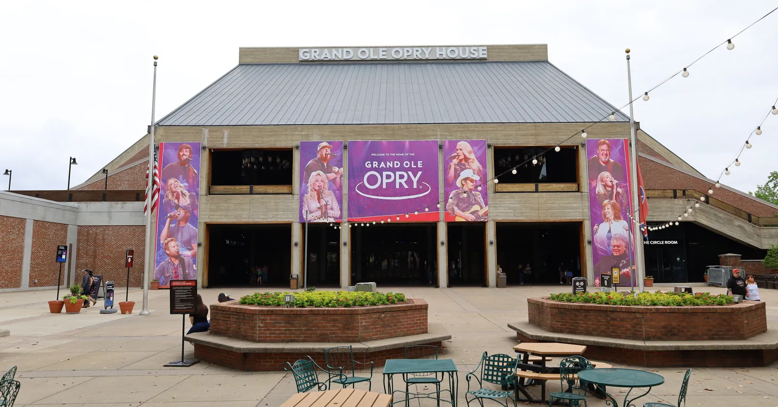 The front of the Grand Ole Opry House in Nashville, a low brick building with its name in raised lettering above the entrance and show banners hung across the facade