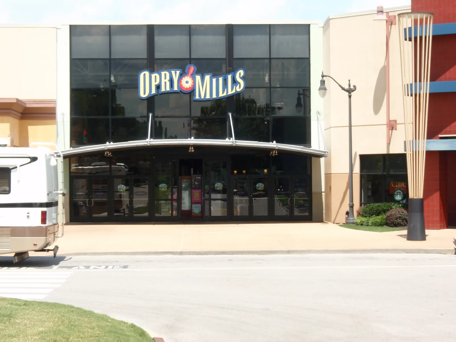 An entrance to the Opry Mills shopping mall in Nashville, a glass frontage with the mall's name in large lettering above a curved canopy over the doors