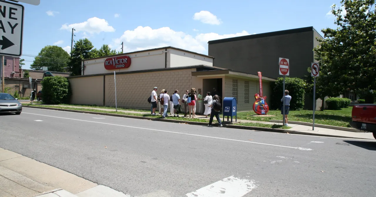 The low brick and block exterior of RCA Studio B on Roy Acuff Place in Nashville, with a small tour group waiting on the pavement outside the door