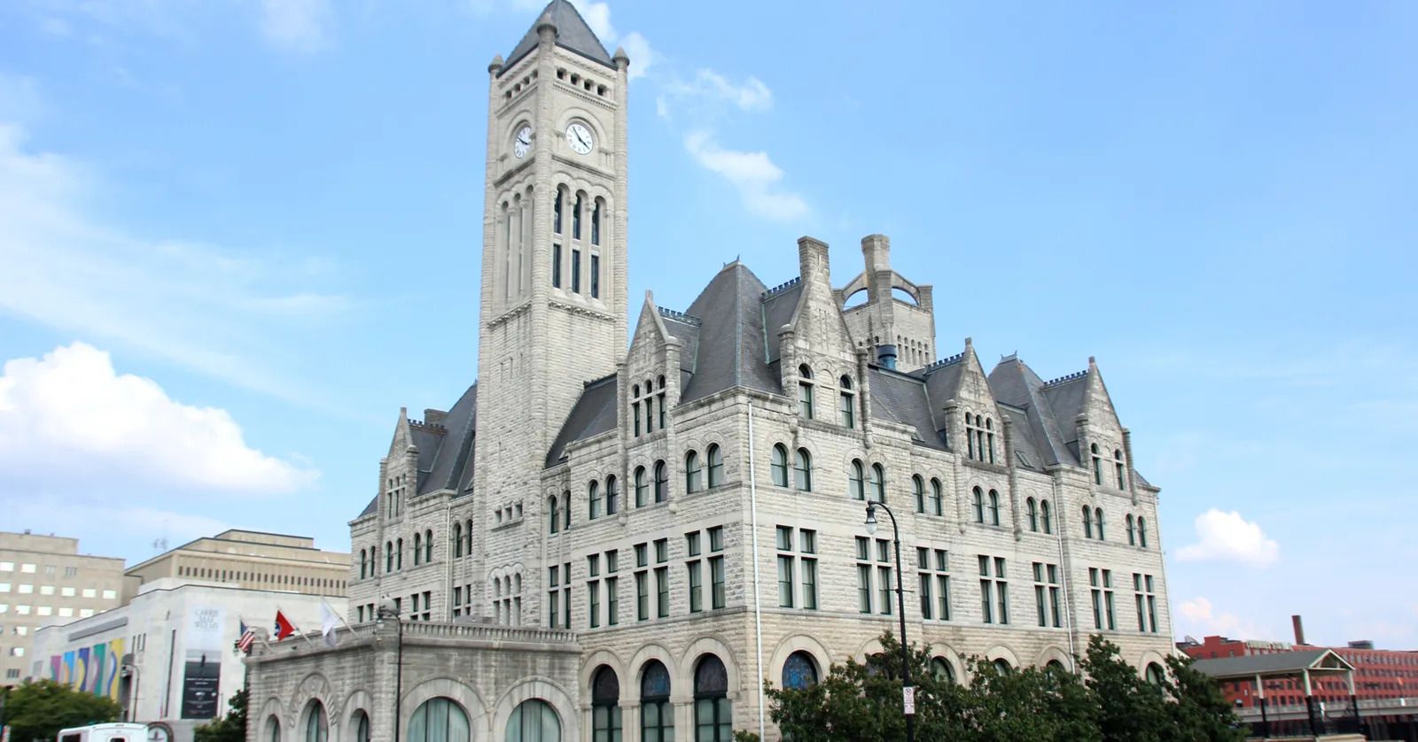 Nashville's Union Station, a grey stone Romanesque Revival building with steep gables and a tall clock tower, seen from Broadway under a blue sky