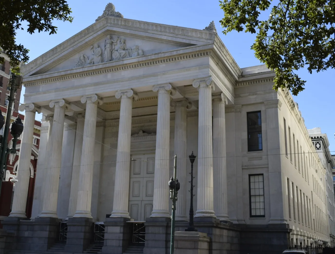 Gallier Hall on St. Charles Avenue in New Orleans, a white marble Greek Revival building with a row of tall Ionic columns under a sculpted pediment