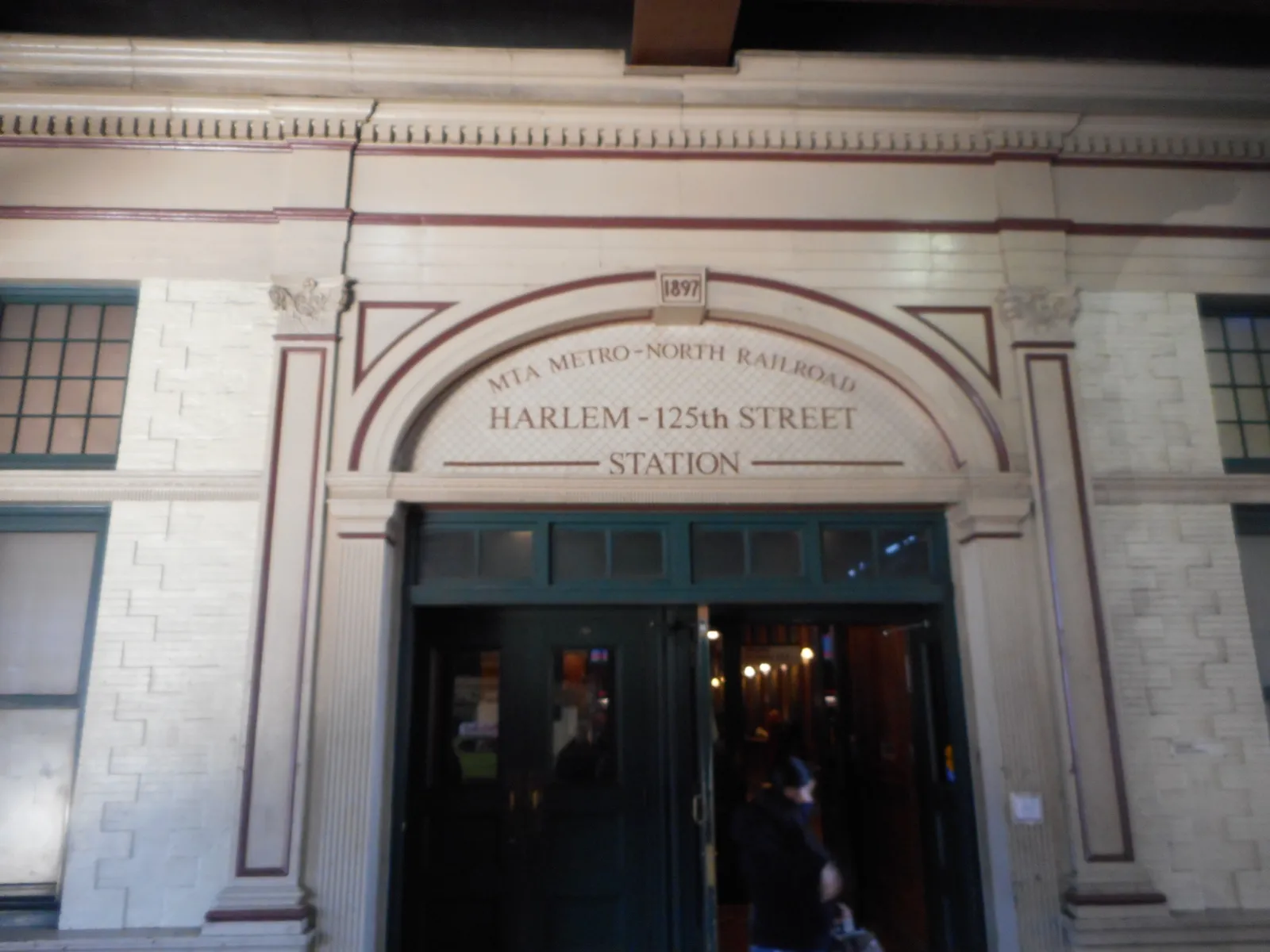 The street entrance of Harlem-125th Street station, HARLEM - 125th STREET STATION carved into the stone arch above the doors with the date 1897 in the keystone