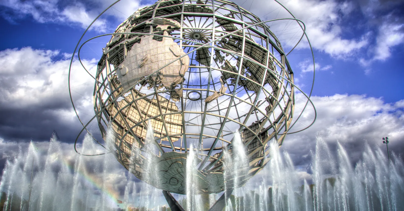 The Unisphere in Flushing Meadows, a giant open steel globe with the continents raised on its surface and three rings circling it, fountains playing in the pool at its base