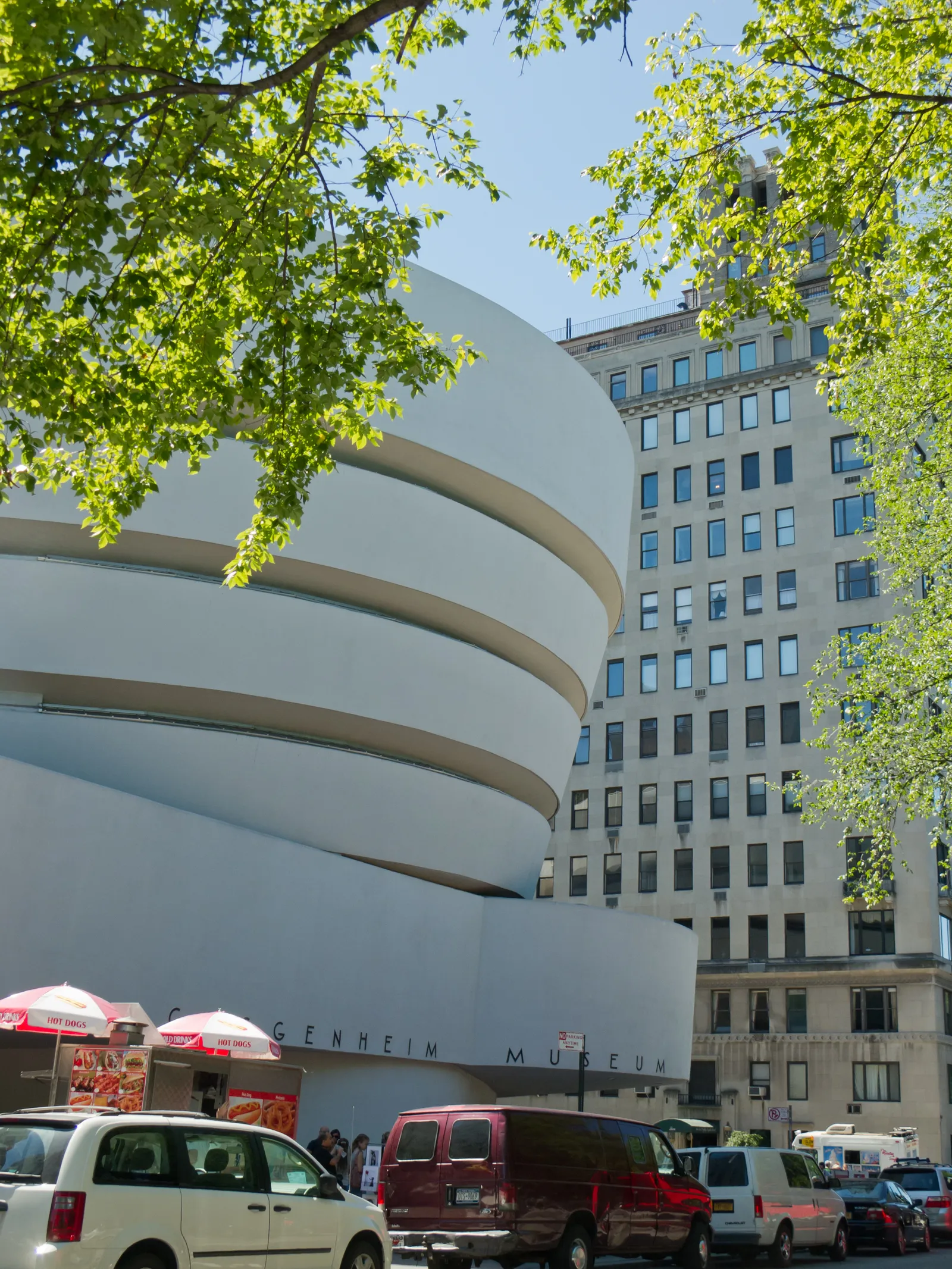 The Solomon R. Guggenheim Museum on Fifth Avenue, a white concrete drum widening as it rises, with the museum's name in letters along the low wing beside it