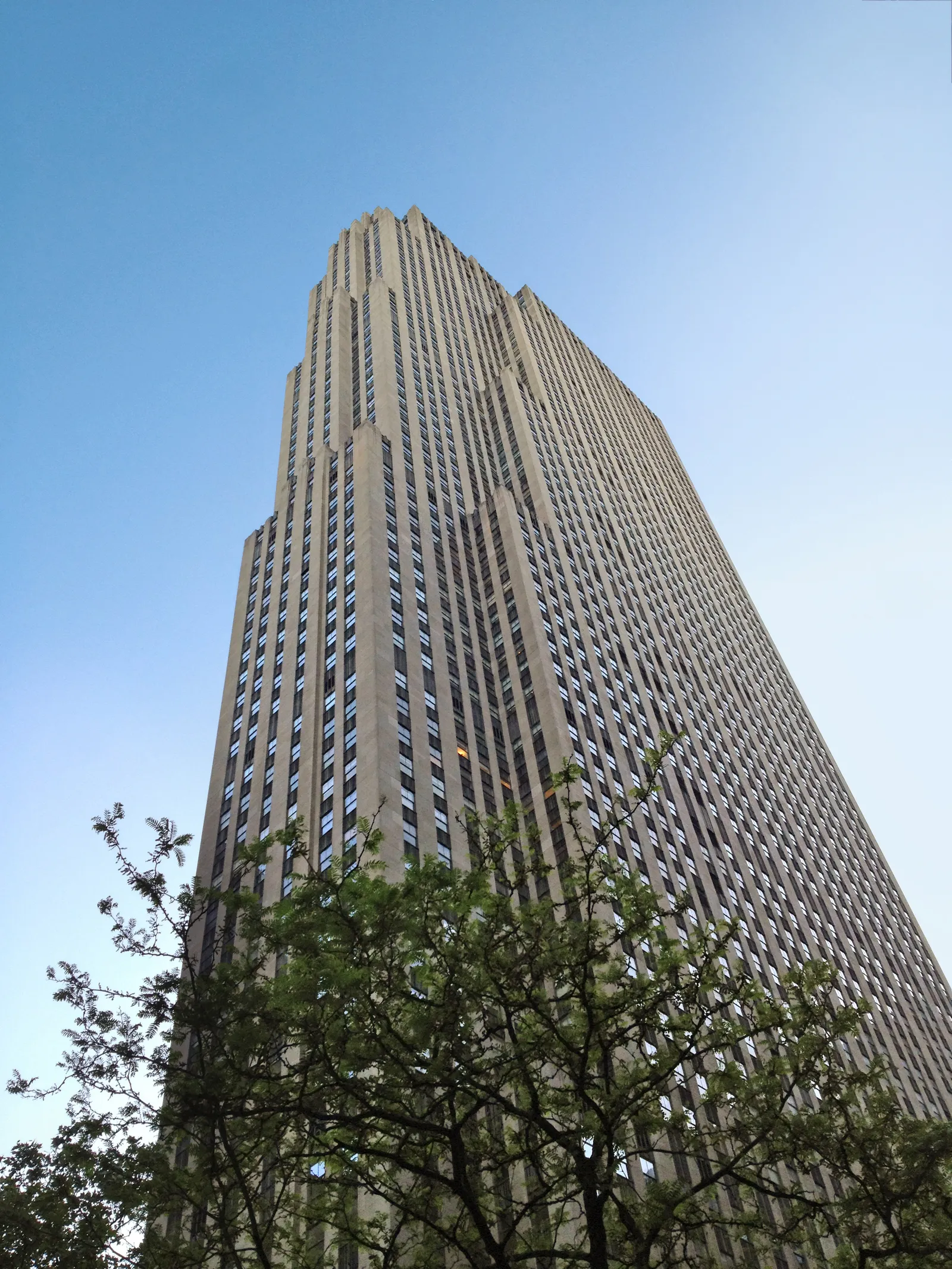 The limestone slab of 30 Rockefeller Plaza seen from street level, its Art Deco setbacks stepping back toward the roof where the observation deck sits