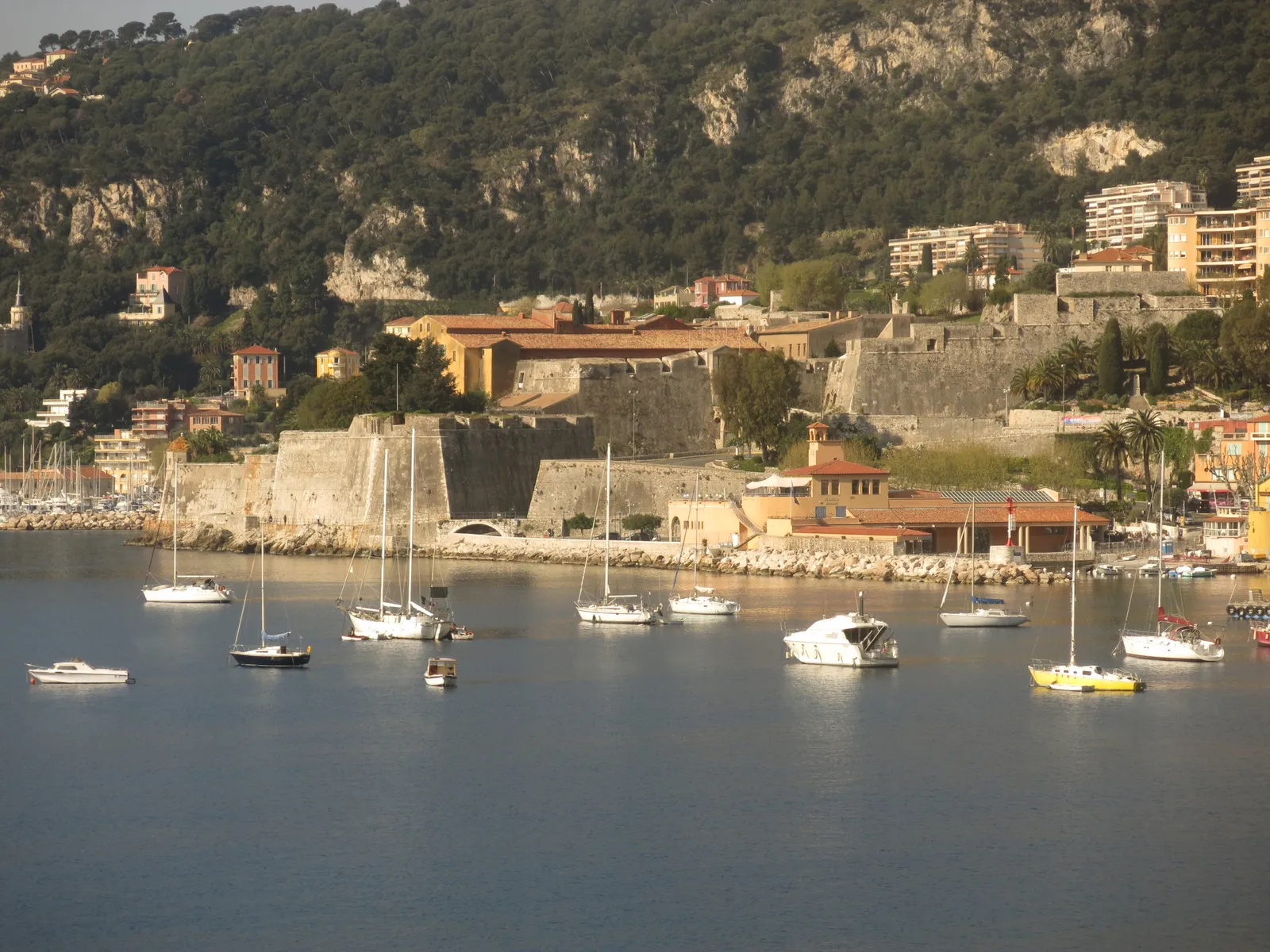 The star-shaped stone walls of the Citadelle Saint-Elme in Villefranche-sur-Mer, seen across the harbor with sailboats moored in front