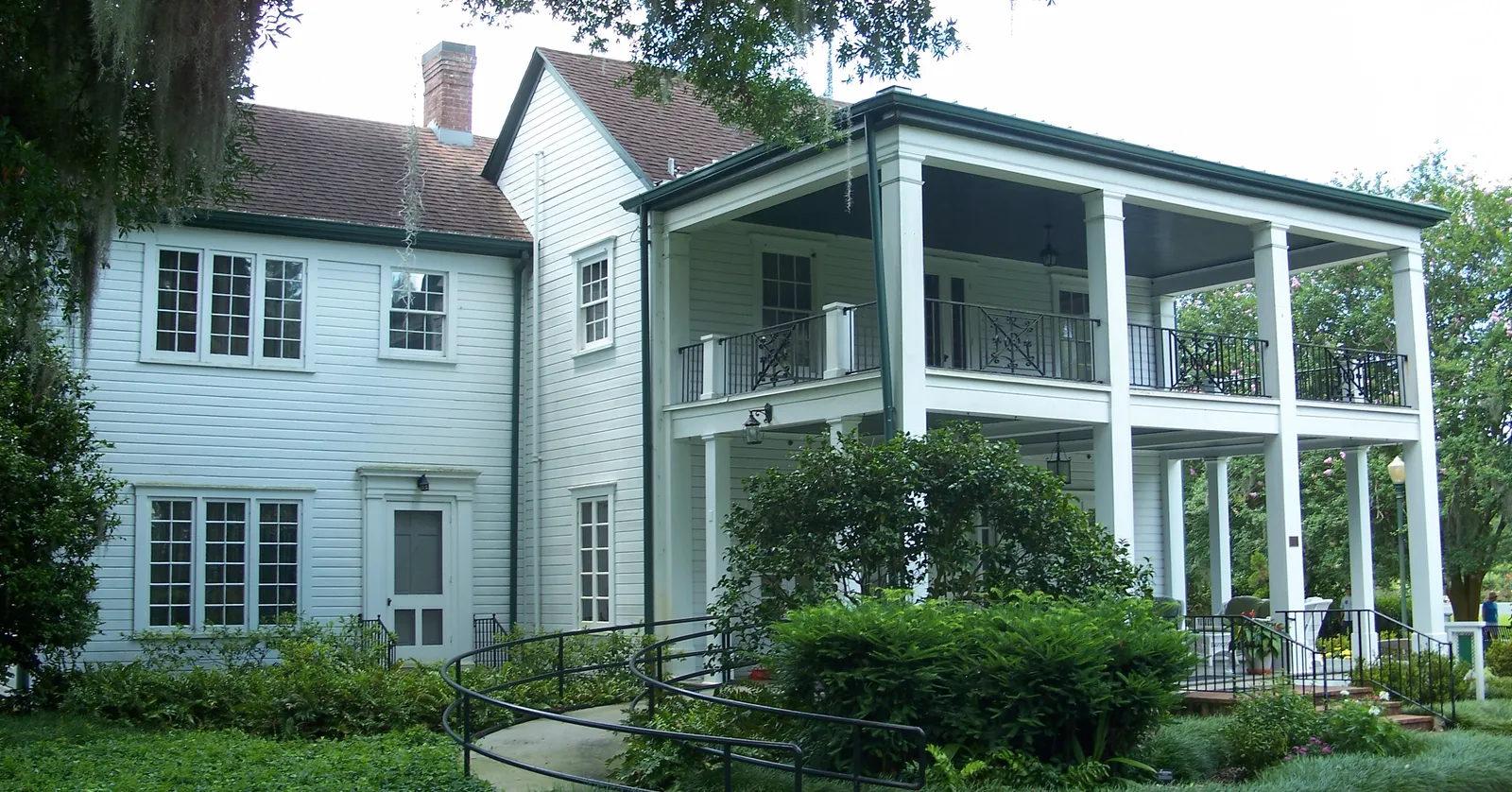 The white clapboard Leu House at Harry P. Leu Gardens in Orlando, its two-storey verandah facing clipped hedges under moss-hung oaks