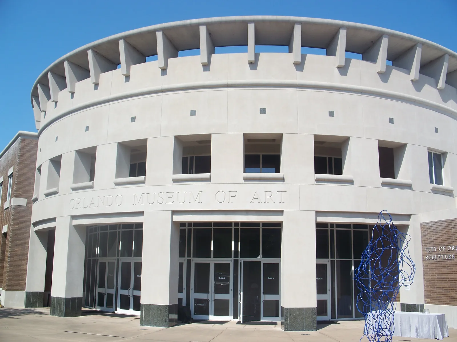 The curved pale concrete entrance front of the Orlando Museum of Art, its name cut into the stone above the glass doors