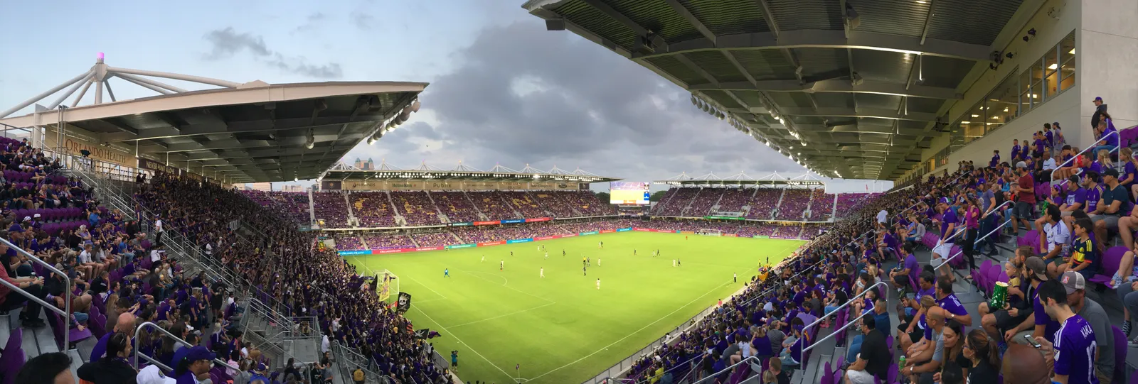 A packed Inter&Co Stadium in Orlando seen from the stands during a match, purple-shirted supporters filling both sides above the green pitch