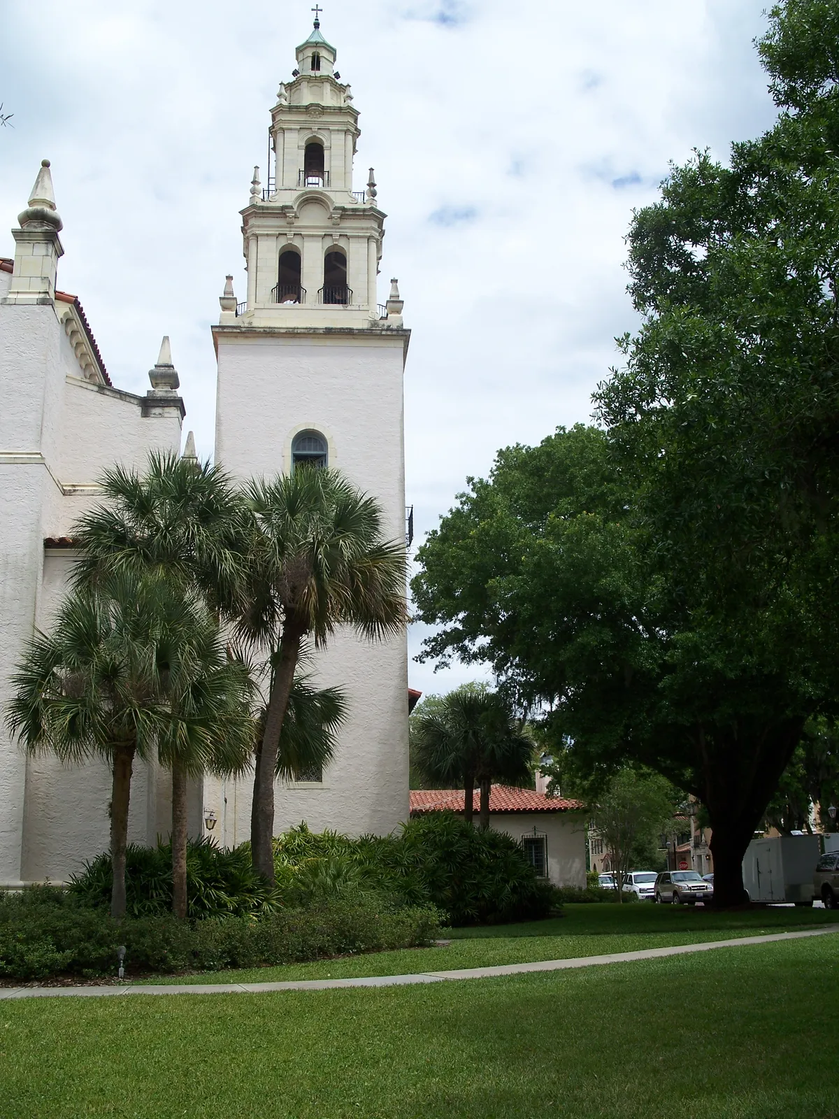 The white bell tower of Knowles Memorial Chapel rising above palm trees and live oaks on the Rollins College campus in Winter Park