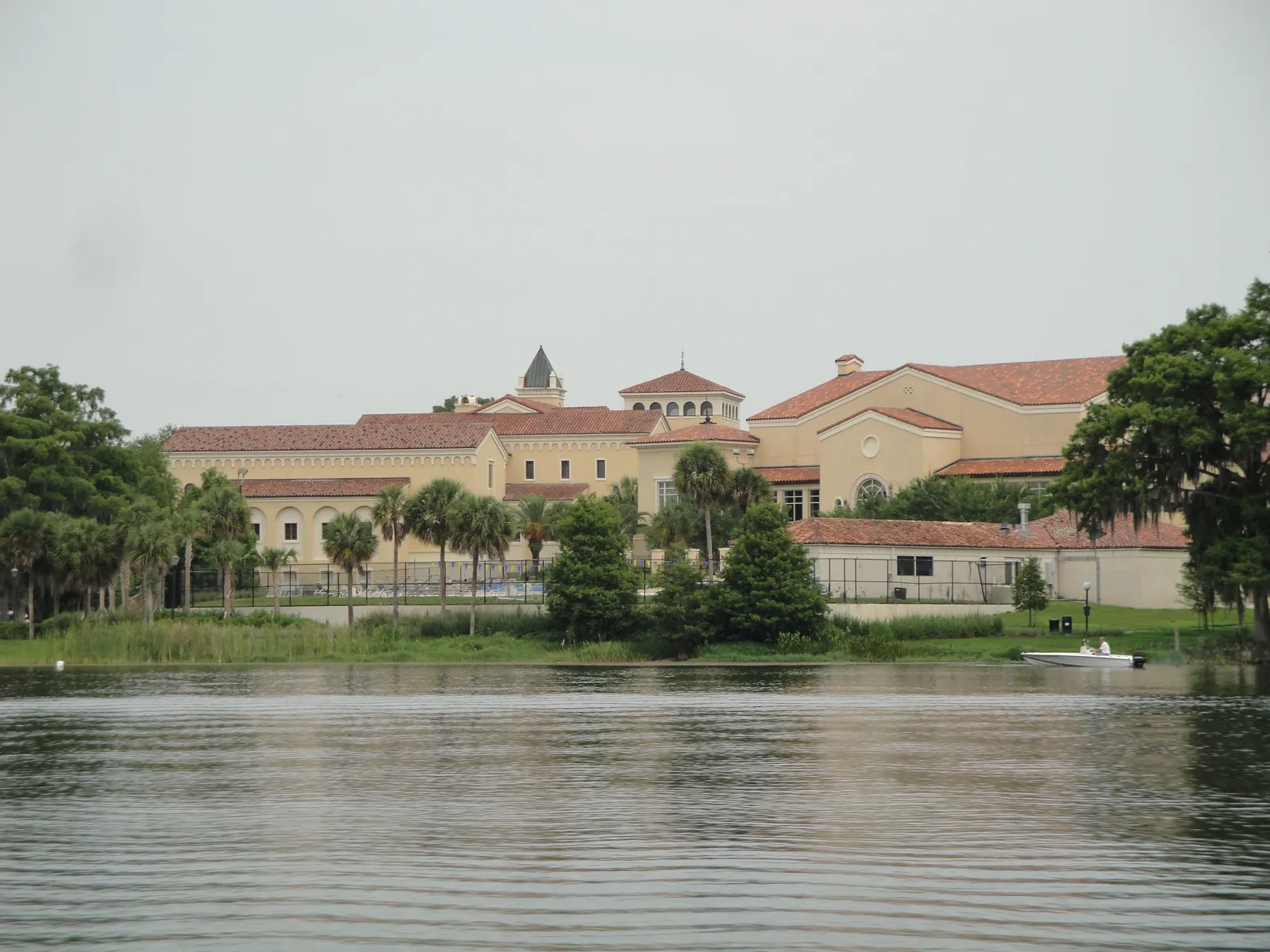 The tiled roofs and arcades of Rollins College seen across the water of Lake Virginia in Winter Park, with a small boat near the far shore
