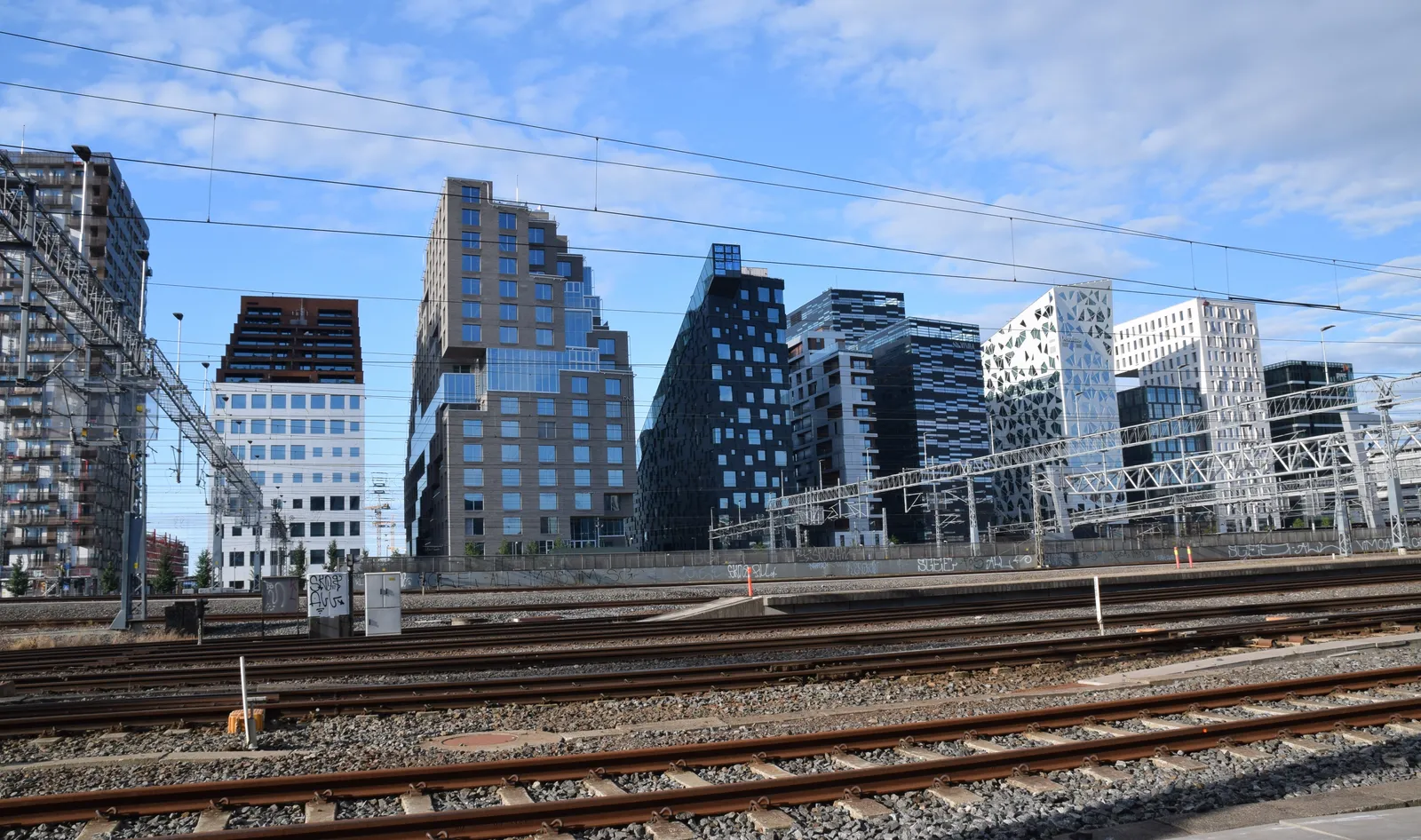 The Barcode row in Oslo seen across the railway tracks from the north side of the central station, a line of narrow high-rise blocks of different heights and facades standing shoulder to shoulder