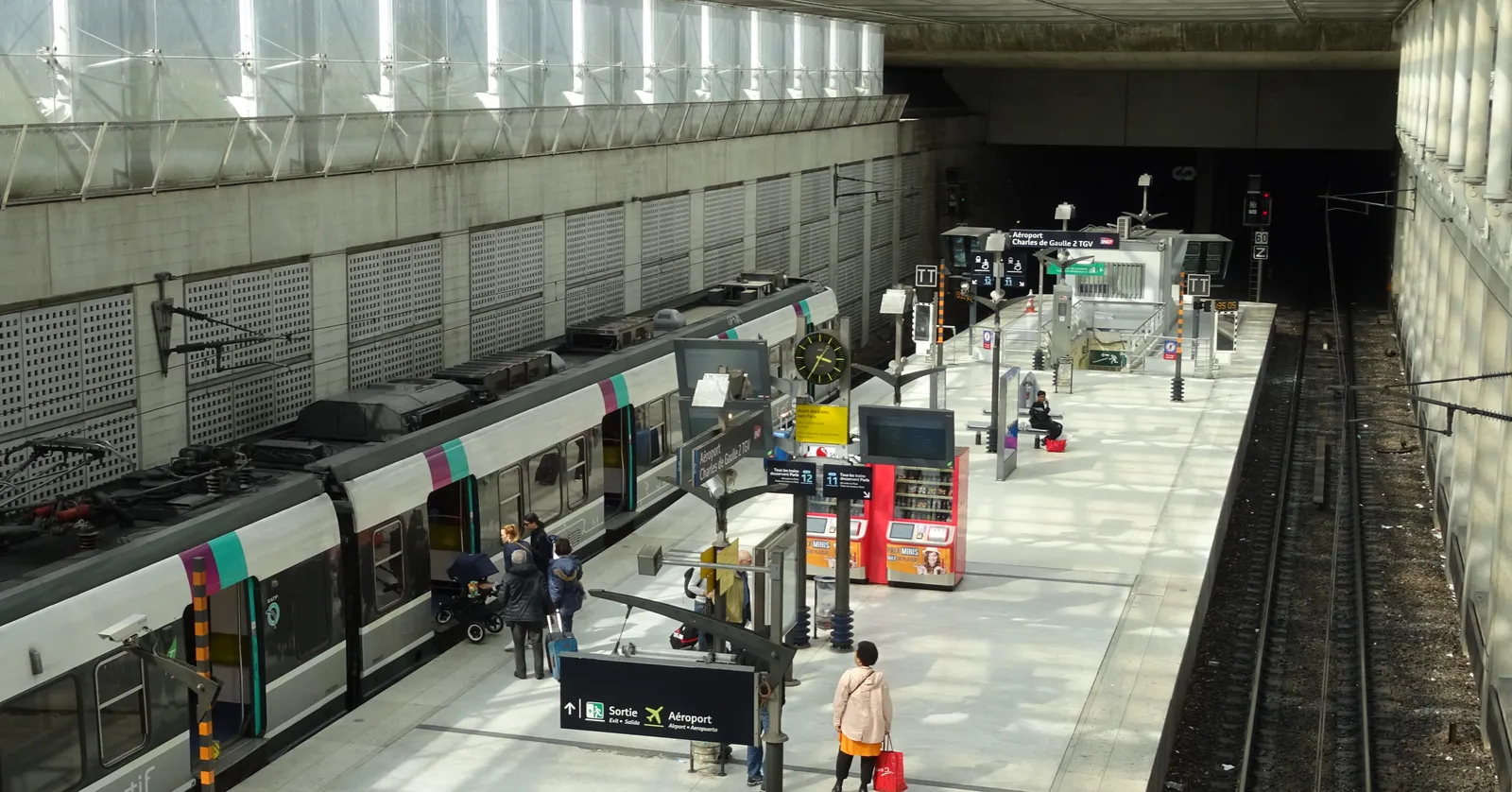 The RER B platform at Paris Charles de Gaulle airport's Terminal 2 station, seen from above, with a suburban train at the platform under a glazed roof
