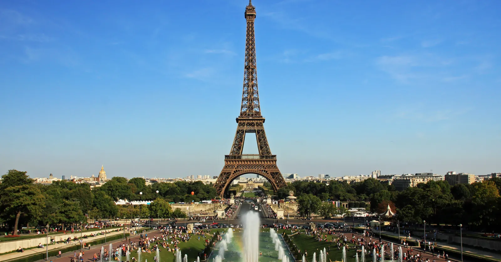 The Eiffel Tower seen head-on from the Trocadéro terrace in Paris, with the Warsaw fountains playing across the sloping gardens between the viewpoint and the river