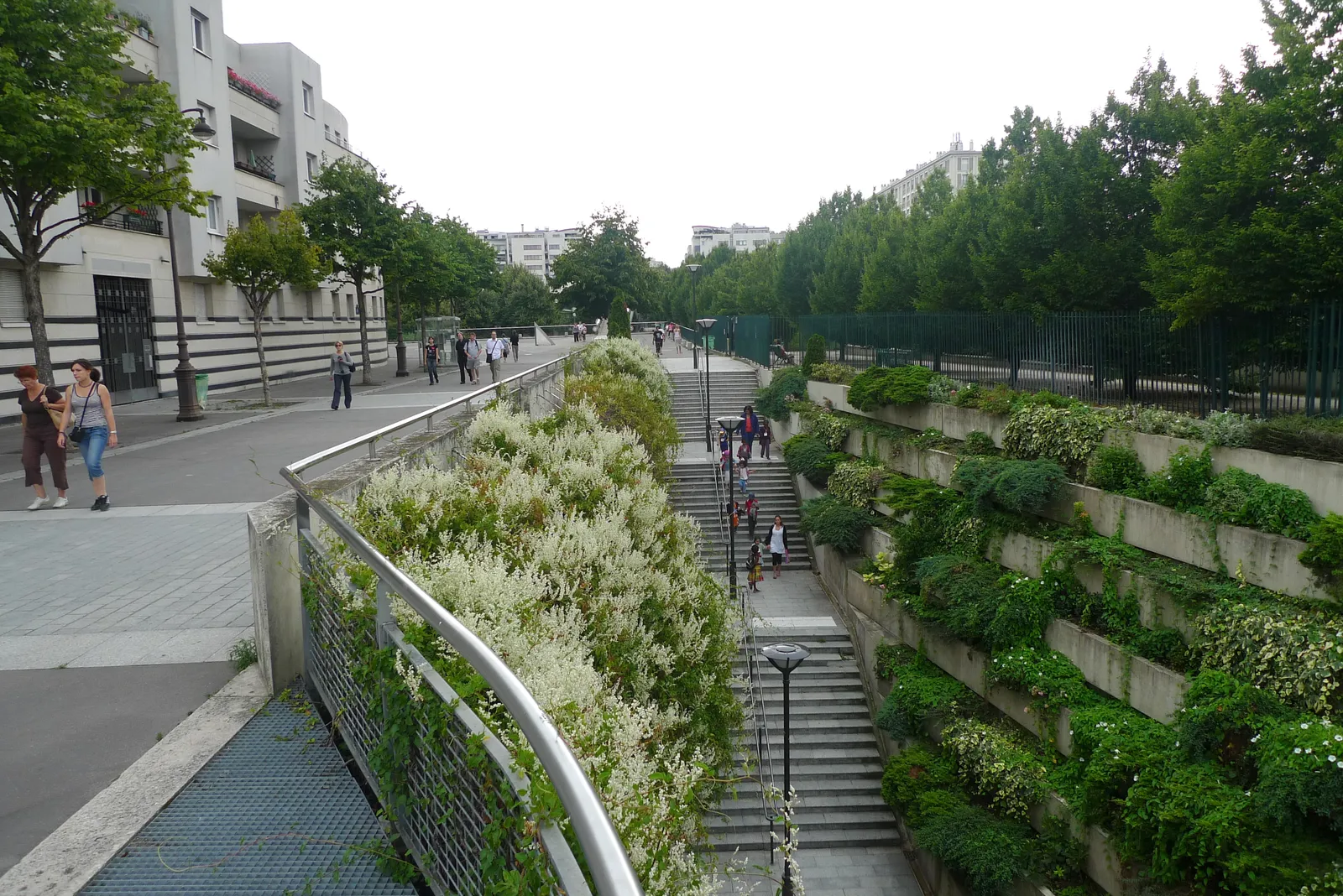 The Coulée verte René-Dumont in Paris running along the top of its viaduct, planting terraced down the retaining wall beside it and a staircase dropping to the street below