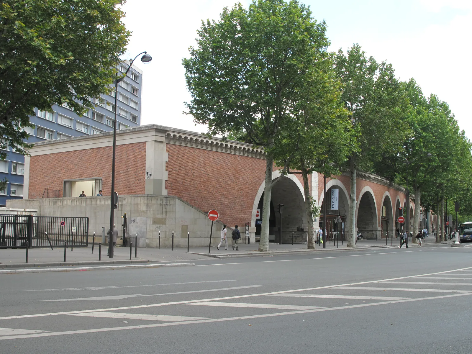 The brick arches of the Viaduc des Arts on Avenue Daumesnil in Paris, each one glazed in as a workshop frontage, with the planted walkway running along the top of the viaduct