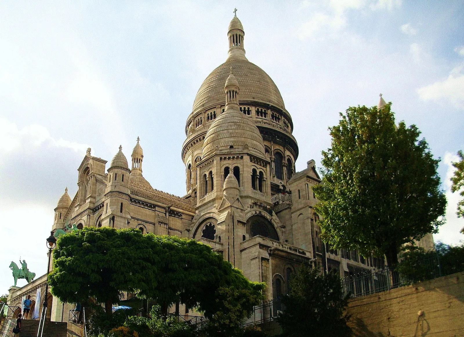 The white domes of Sacré-Cœur basilica rising above trees on the Montmartre hilltop in Paris
