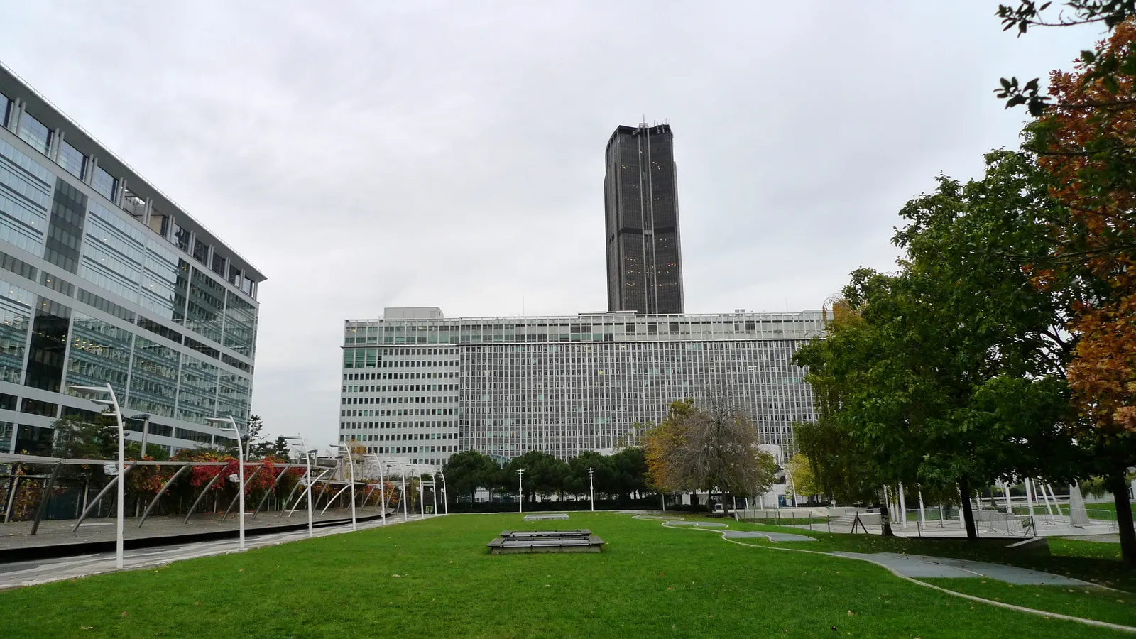 The lawn and paved walkways of the Jardin Atlantique on the roof slab above the platforms at Paris Gare Montparnasse, with the Tour Montparnasse rising behind the office blocks around it