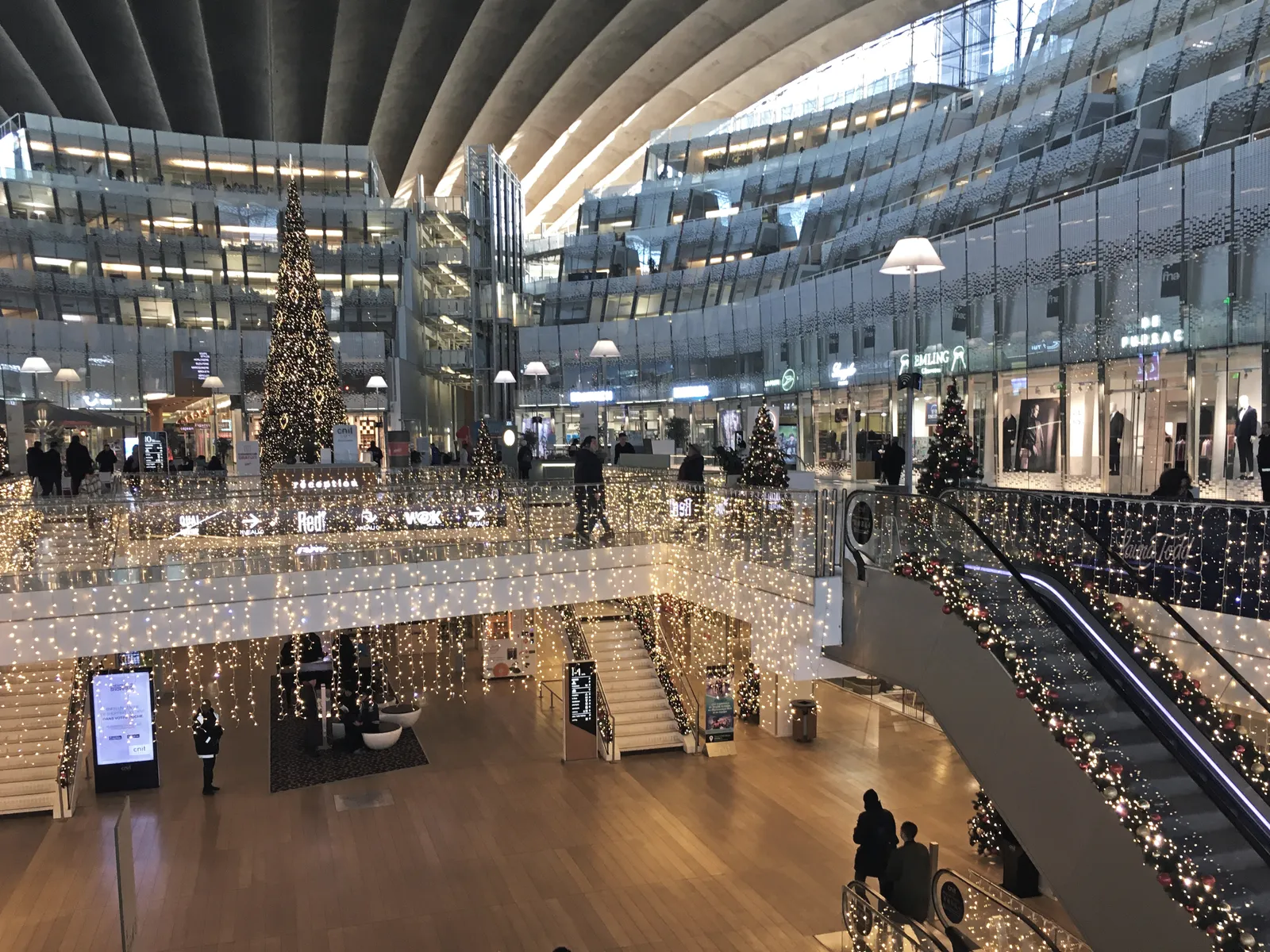 The curved, multi-level glass and concrete interior atrium of the CNIT building at La Défense