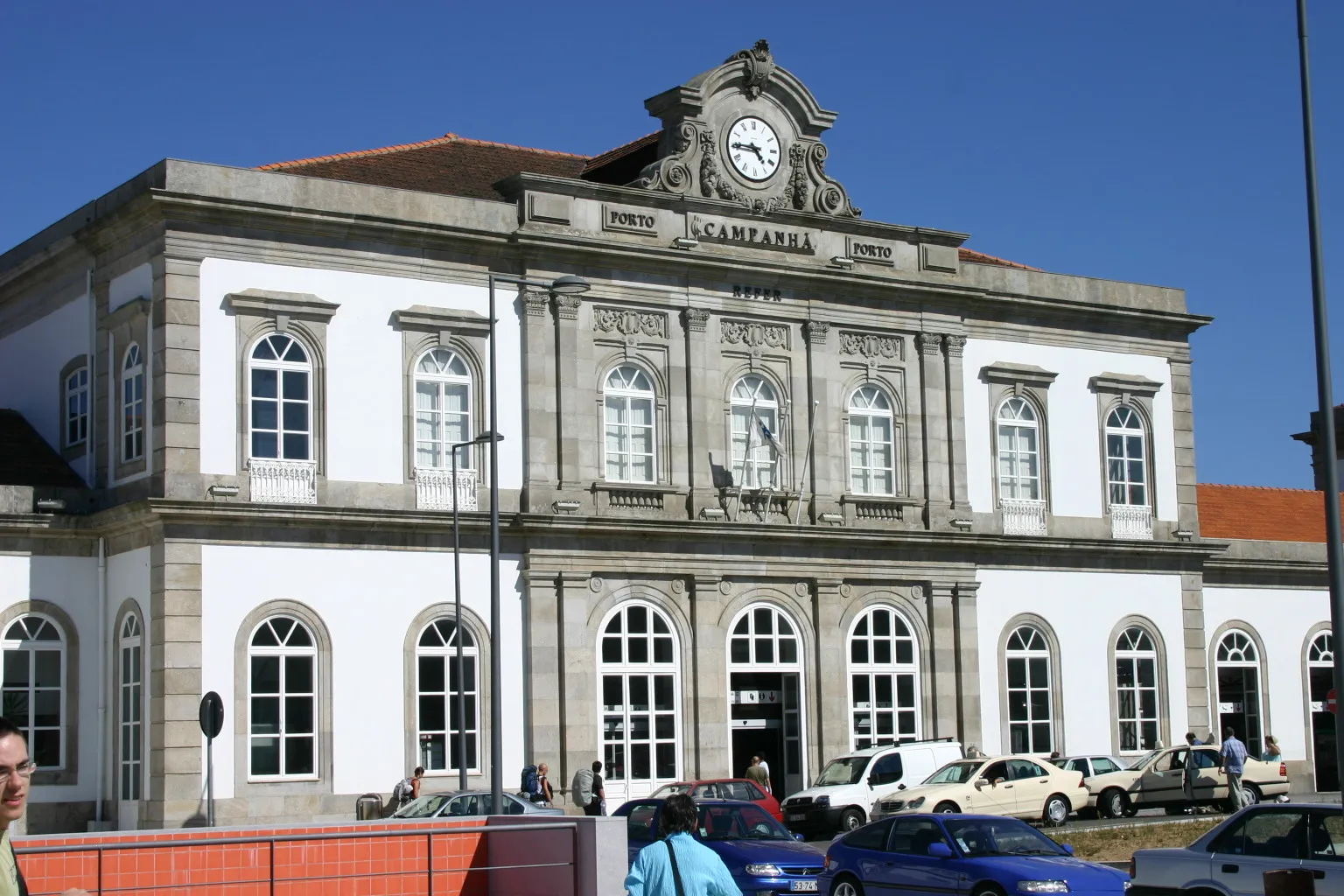 The stone and white facade of Porto Campanhã railway station, with its clock and carved lettering reading Campanhã under a clear blue sky