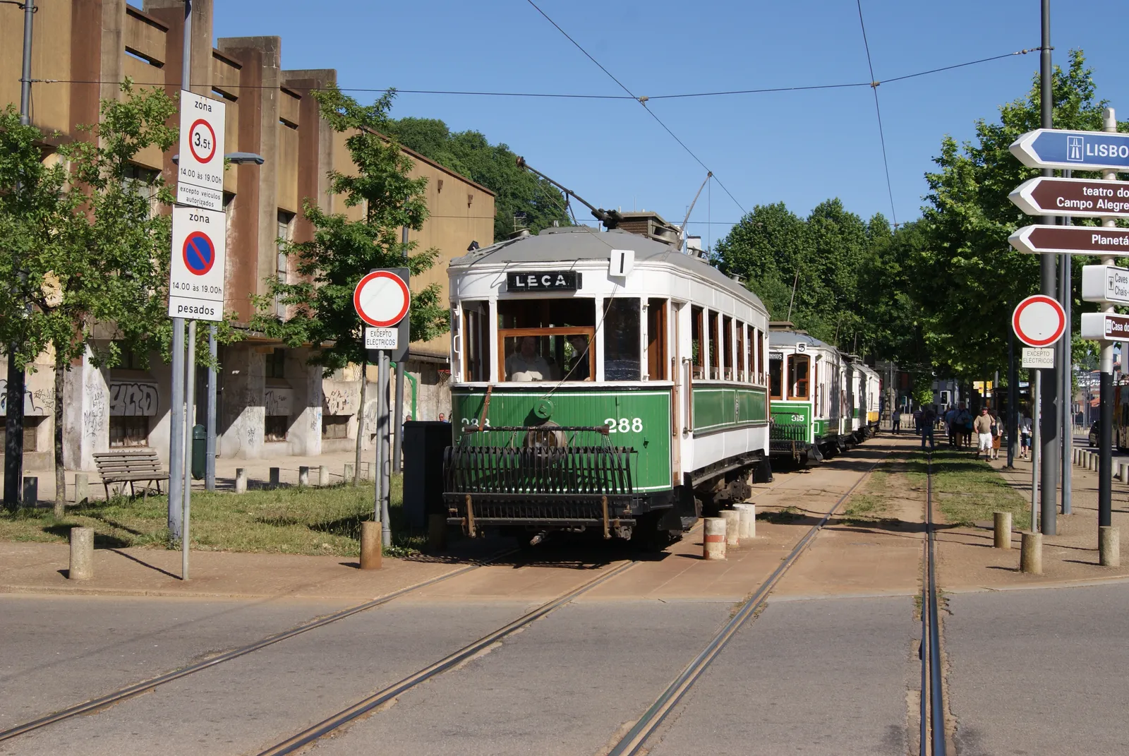 A restored green and cream wooden tram from Porto's historic tram fleet standing at a street terminus with its trolley pole raised