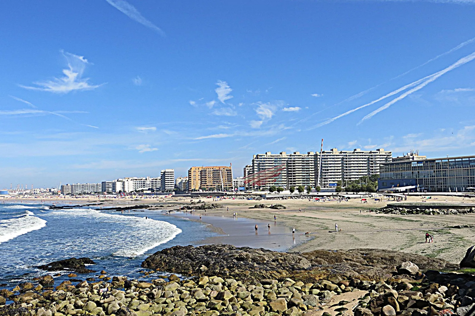 The wide sandy beach at Matosinhos with rocks in the foreground, the Atlantic breaking on the left and a line of seafront apartment blocks behind