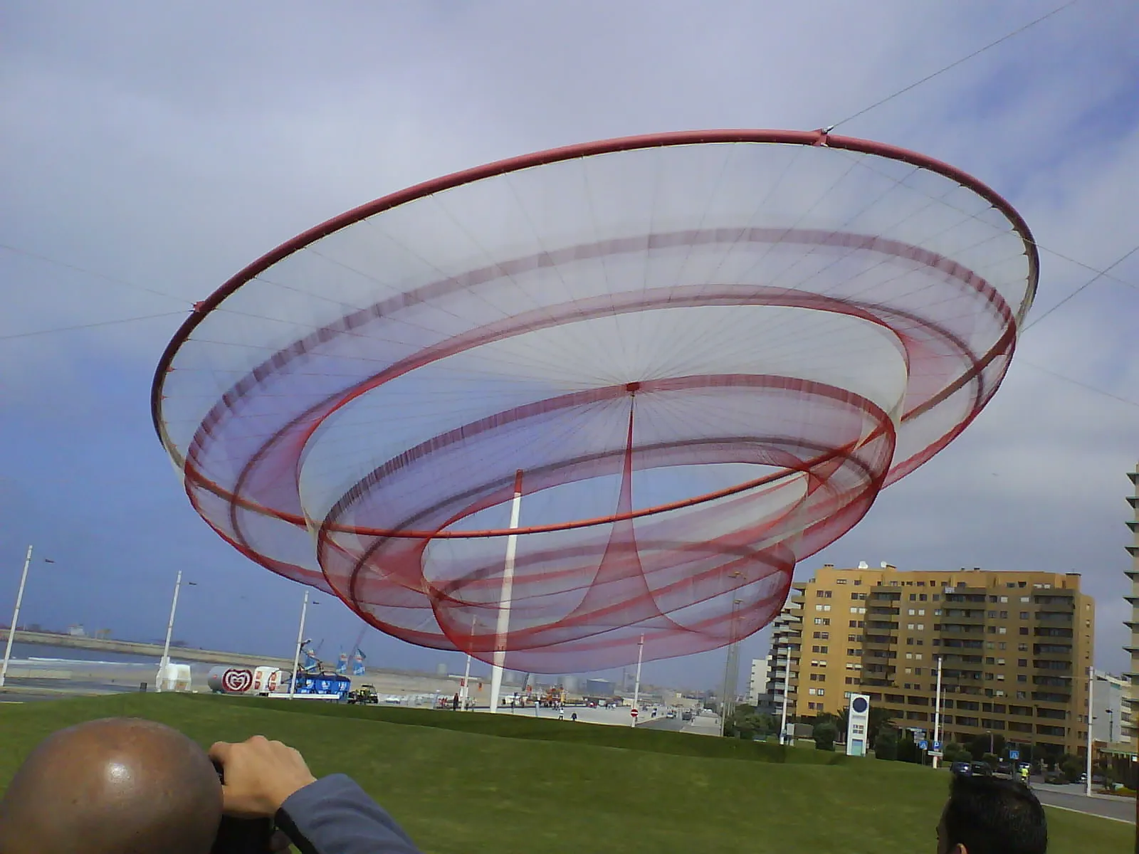 The large red net sculpture She Changes suspended above a grassy roundabout on the Matosinhos seafront