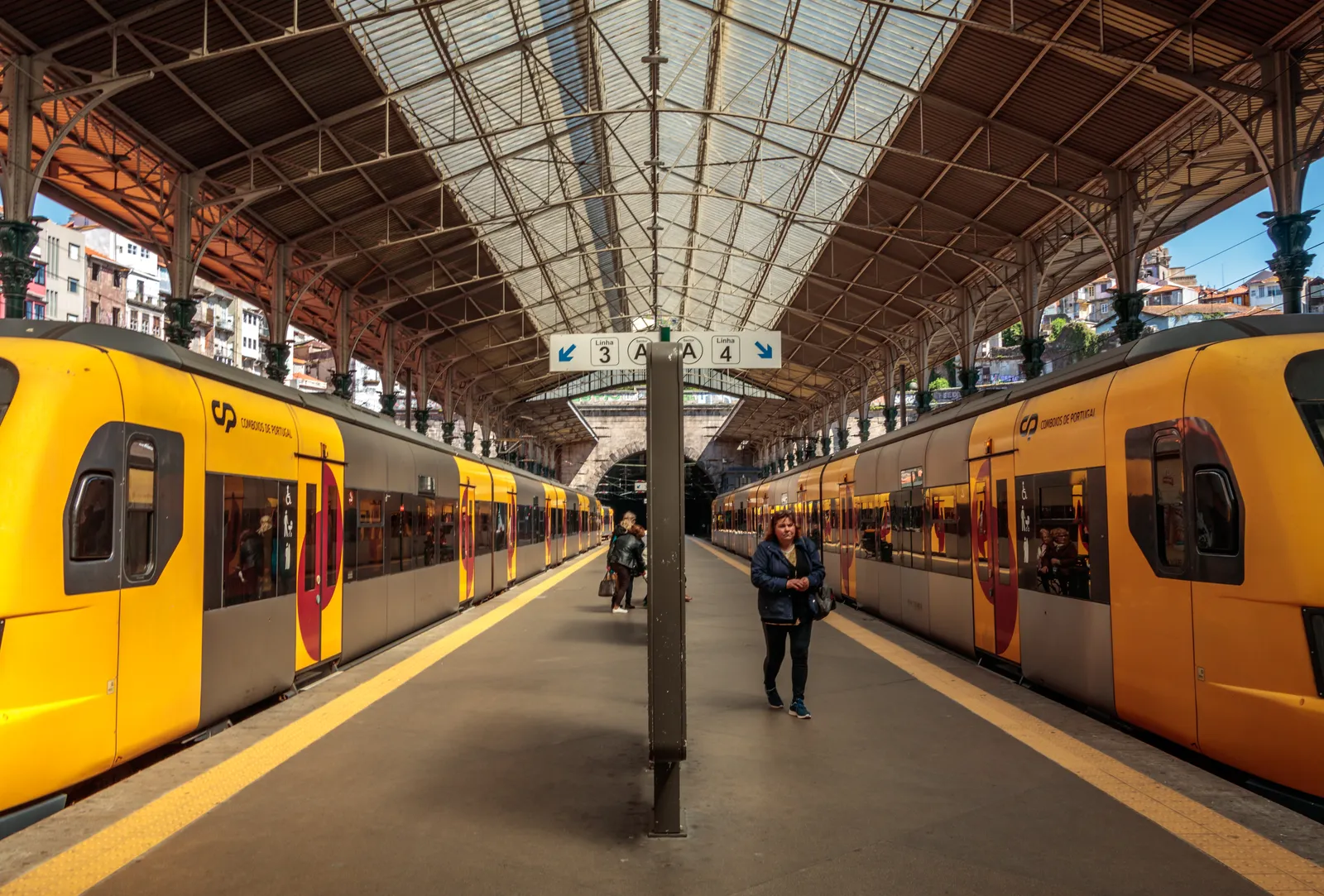 Yellow suburban trains waiting at the platforms of São Bento station in Porto beneath its arched iron and glass roof