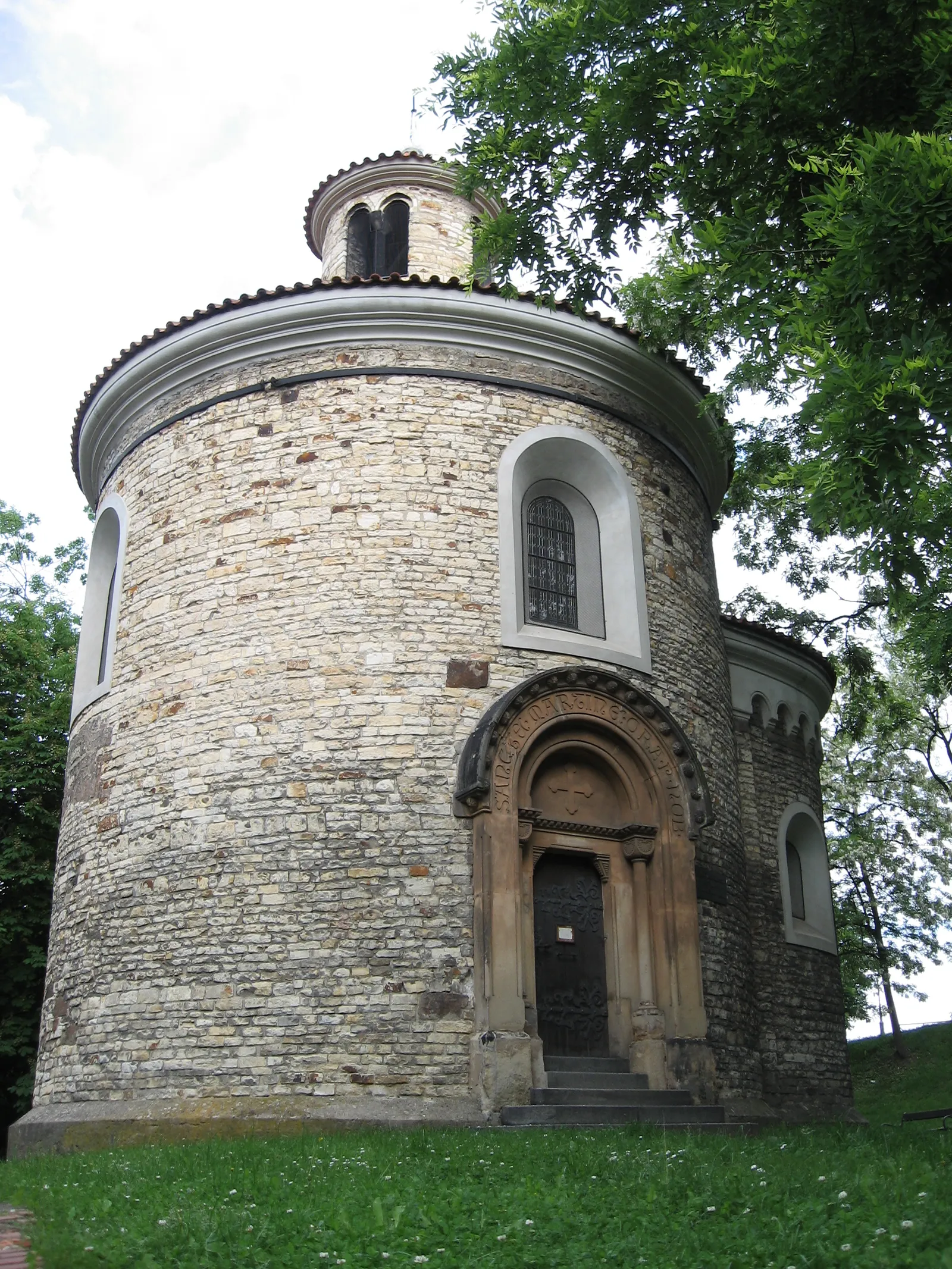 The Romanesque Rotunda of St Martin at Vyšehrad, a small round stone building with a conical roof, a lantern turret on top and a carved stone portal around its door