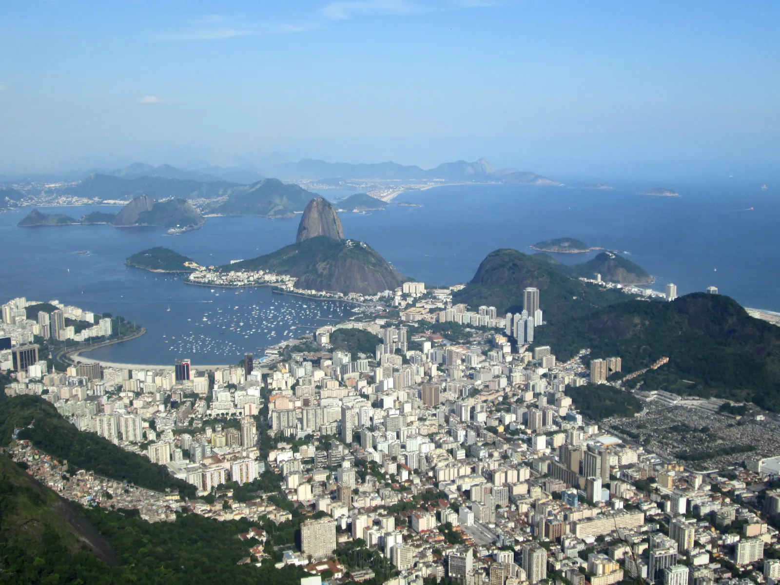 The view from the summit of Corcovado in Rio de Janeiro looking down over the packed blocks of Botafogo, the boat-filled bay and the granite dome of Sugarloaf Mountain at the harbour mouth