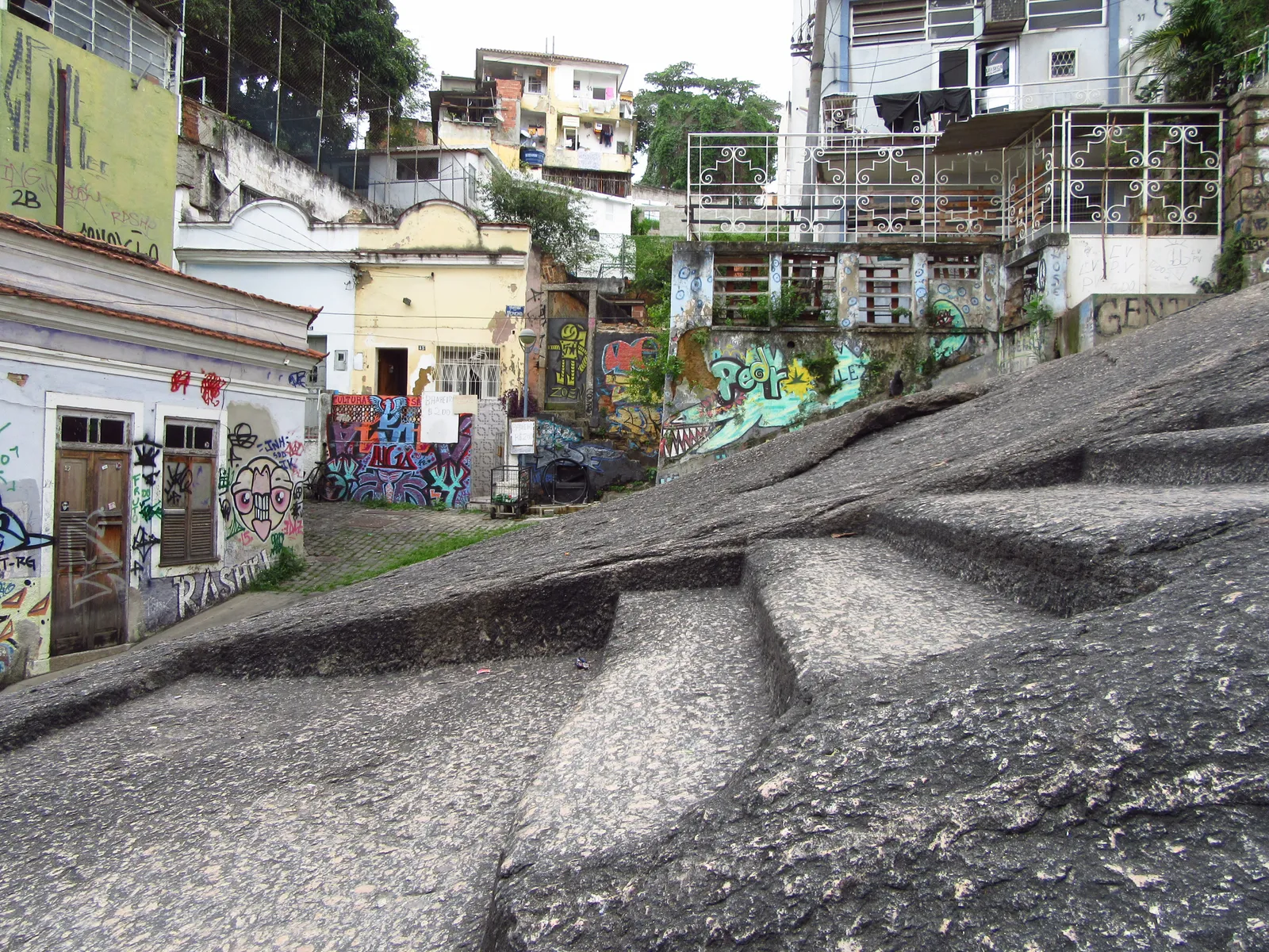 The bare granite slope of Pedra do Sal in Rio de Janeiro, worn steps cut into the rock rising between graffiti-covered houses on the lower slopes of Morro da Conceição