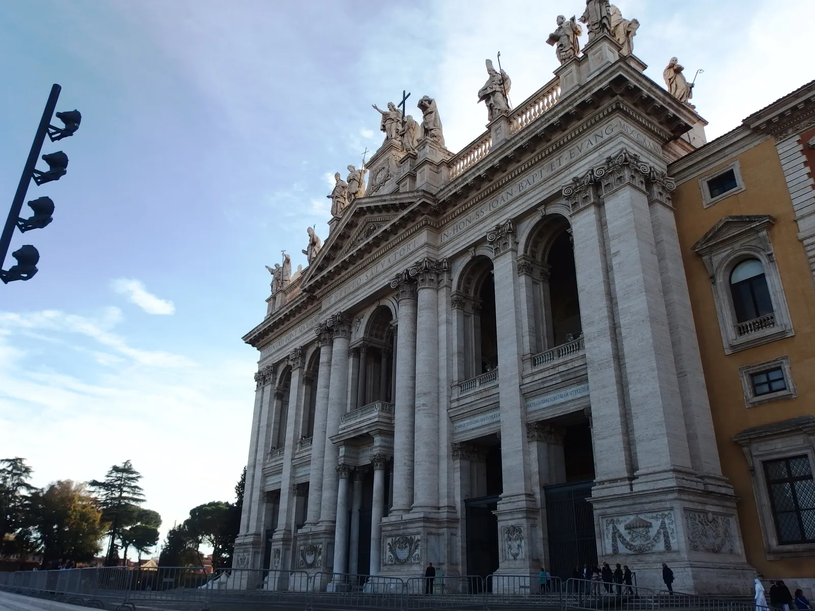 The facade of the Basilica di San Giovanni in Laterano in Rome, with rooftop statues of saints against a blue sky