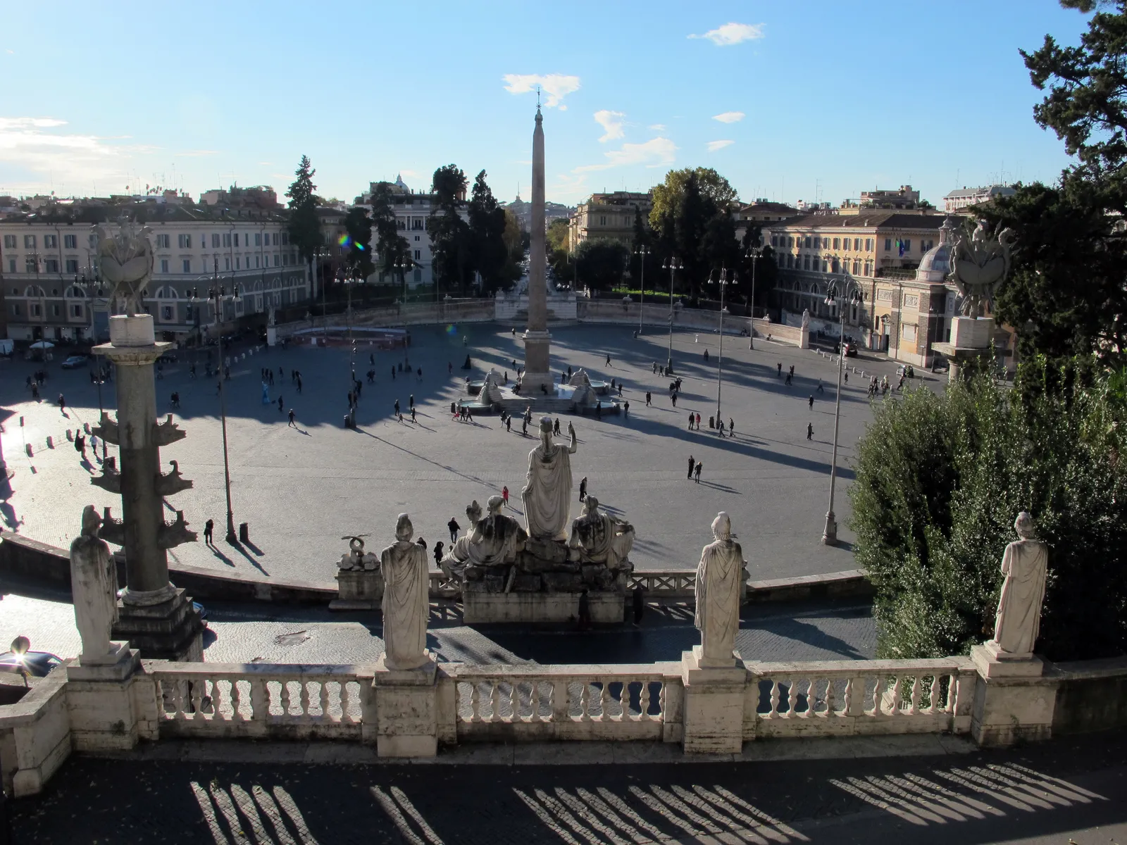 The view from the Pincio terrace in Rome down onto the oval of Piazza del Popolo, its Egyptian obelisk at the centre, seen over a stone balustrade lined with statues