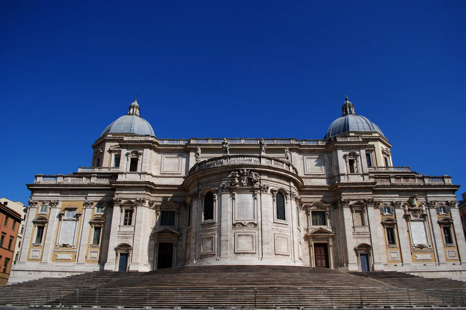 The facade of the Basilica di Santa Maria Maggiore in Rome under a clear blue sky, with its wide entrance steps