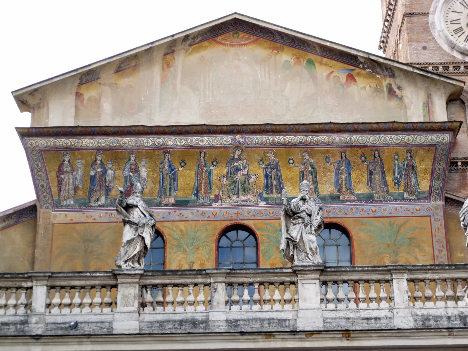 The gold mosaic band across the front of Santa Maria in Trastevere, the Virgin enthroned at the centre with a row of women carrying lamps on either side, with baroque statues standing on the balustrade below it