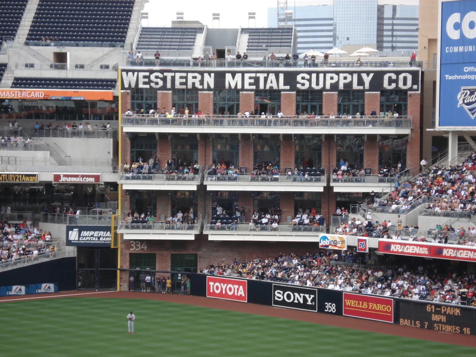 The brick Western Metal Supply Co. building standing inside Petco Park, its name across the roofline and spectators filling the balconies above the left-field wall