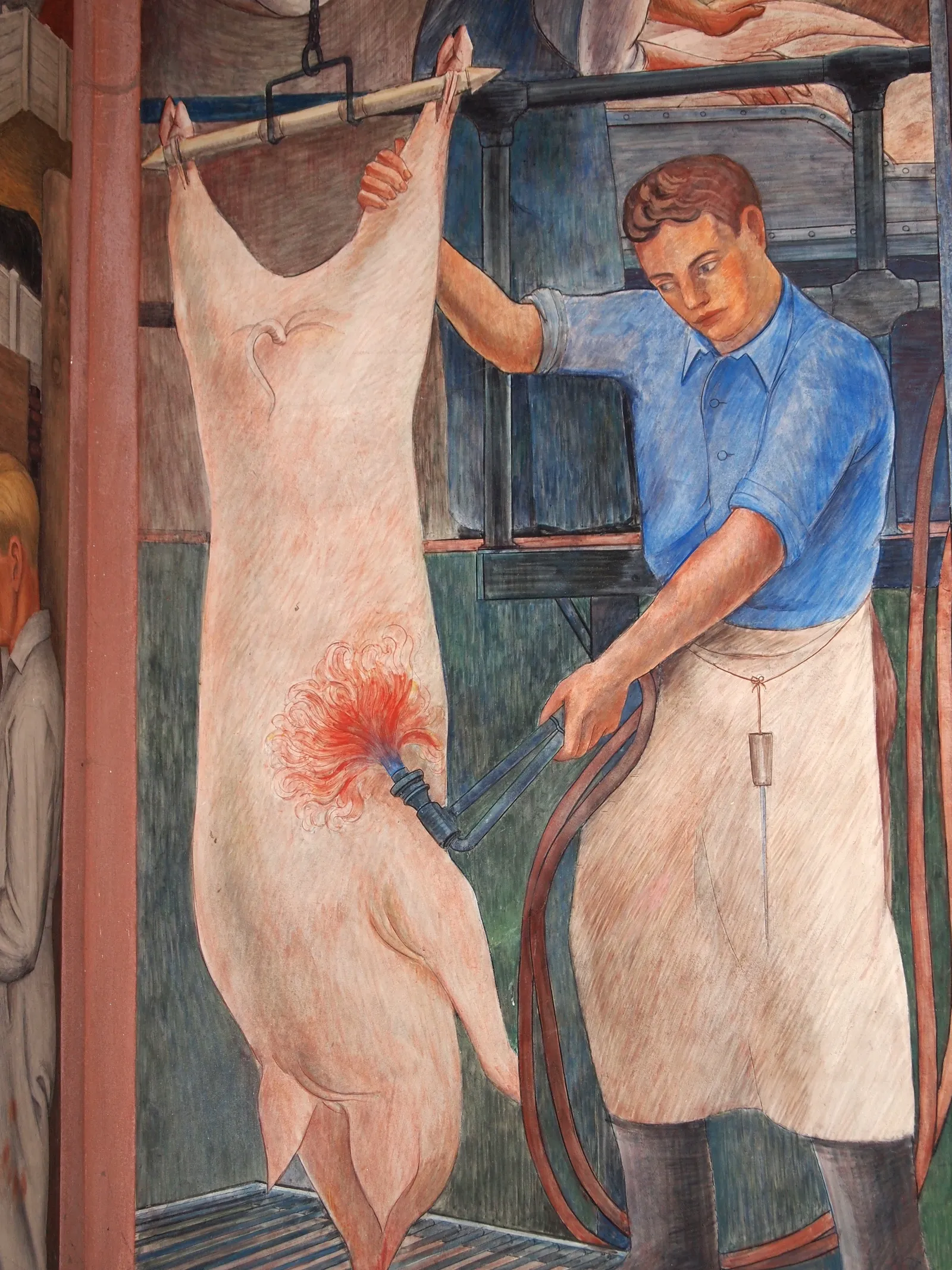 A 1934 fresco inside Coit Tower in San Francisco showing a worker in a blue shirt and apron dressing a carcass on a rail in a meat plant, painted in flat muted colours