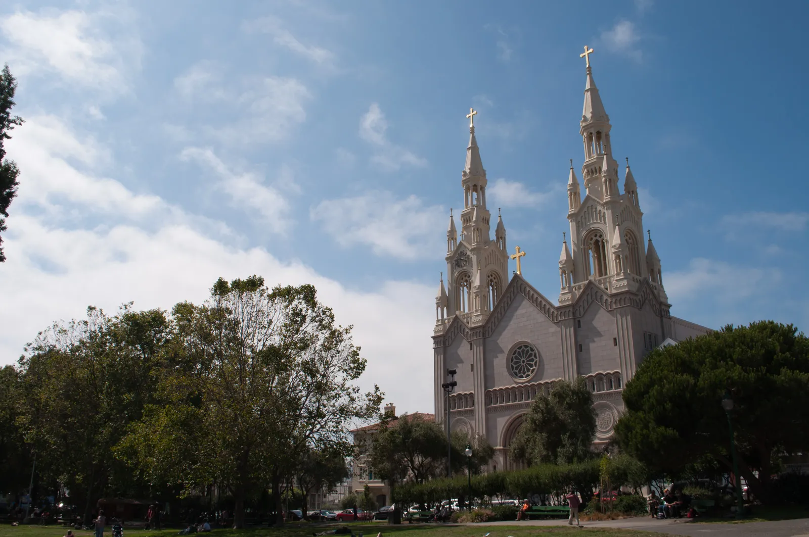 Saints Peter and Paul Church on Washington Square in San Francisco's North Beach, a white twin-spired church seen across the park's lawns and trees under a blue sky