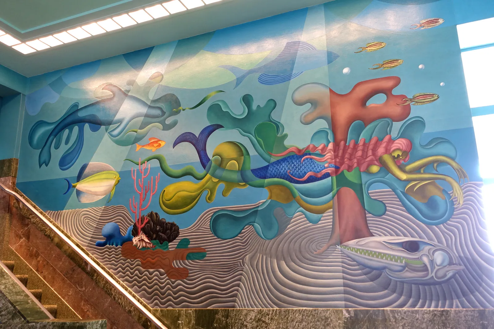 Hilaire Hiler's undersea mural inside the Aquatic Park Bathhouse in San Francisco, an octopus, fish and coral painted in soft blues and pinks across a wall above a staircase