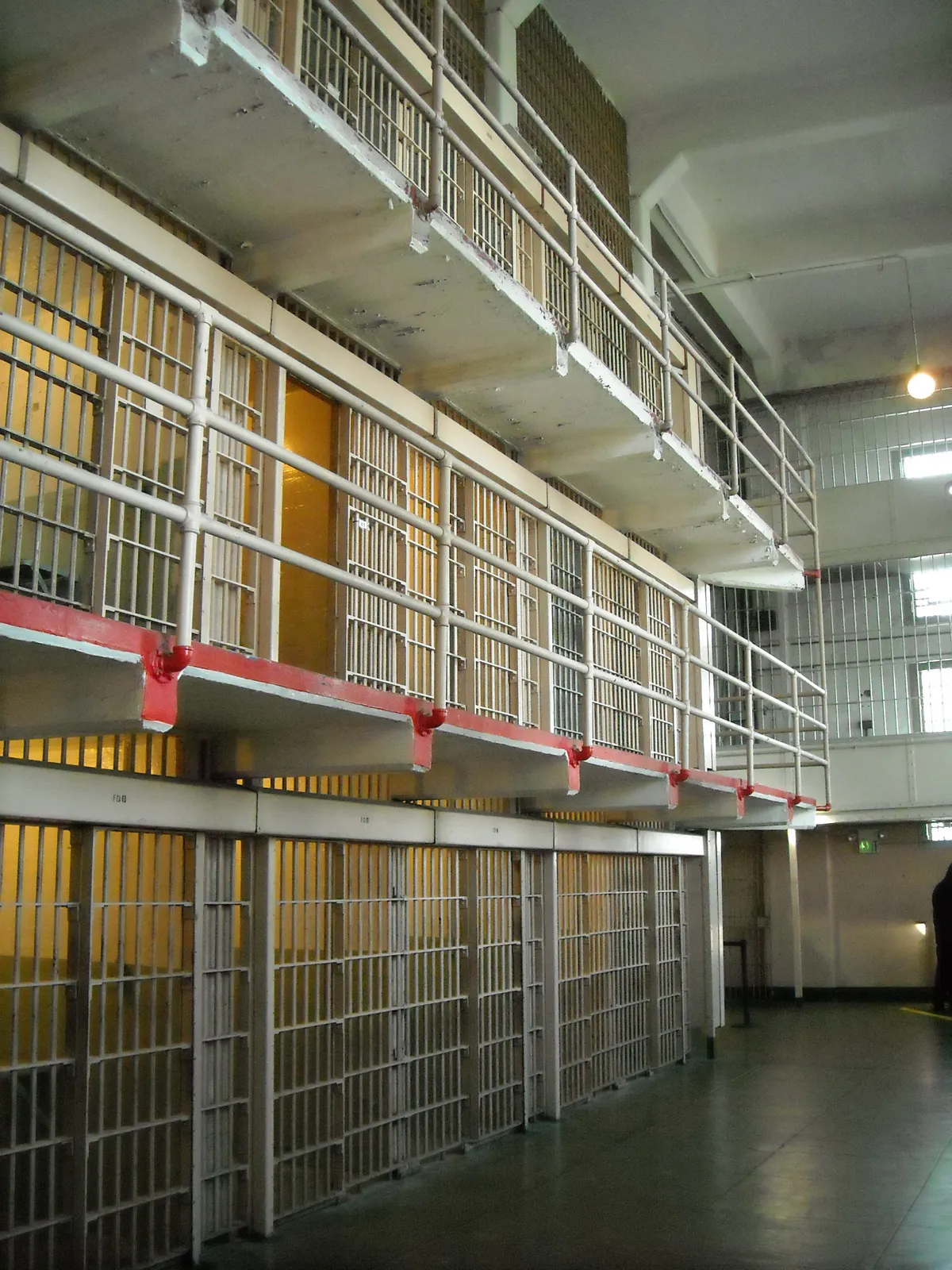 Three tiers of barred cells along a corridor inside the main cellhouse of the former Alcatraz prison, with railed walkways along the upper floors
