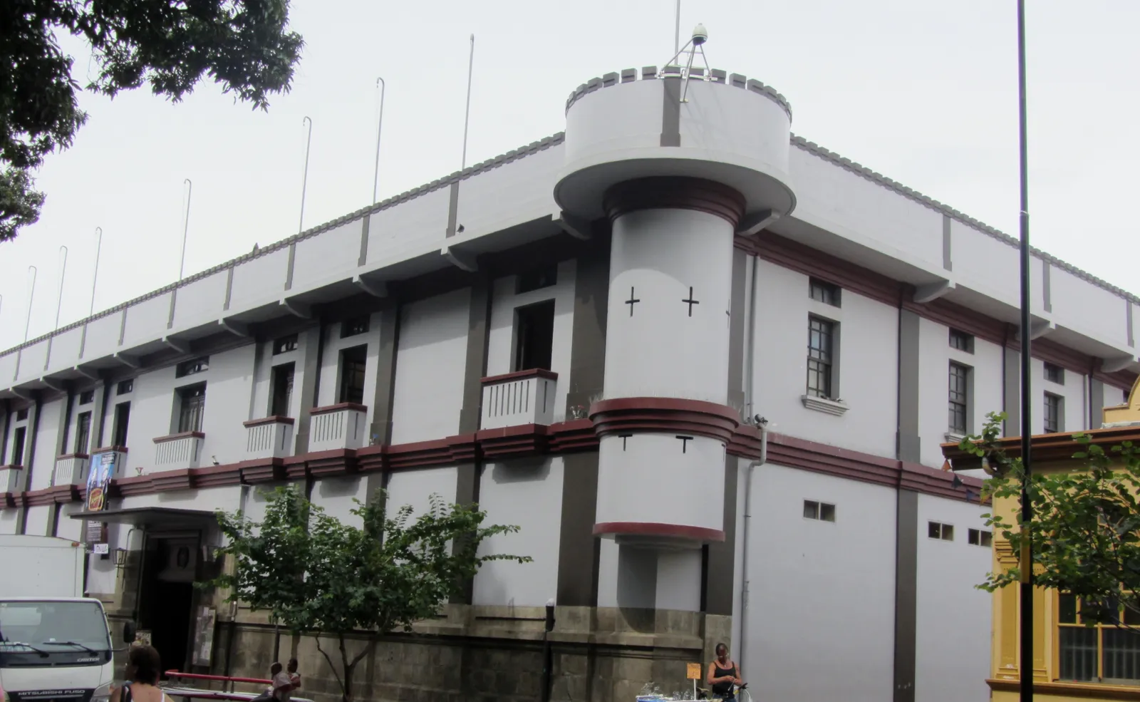 The white two-storey former arms barracks in Alajuela, now the Juan Santamaría museum, with a rounded corner turret and dark red trim along its walls