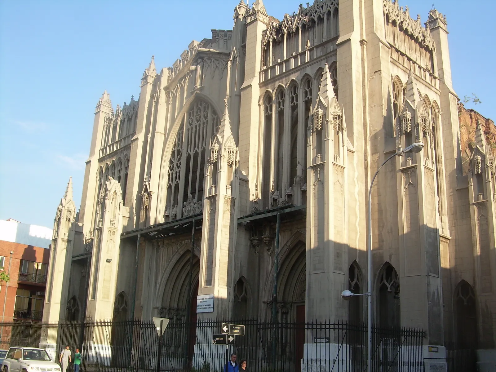 The grey neo-gothic west front of the Basílica del Salvador in Santiago, with pointed arches, pinnacles and railings closing off the pavement in front of it