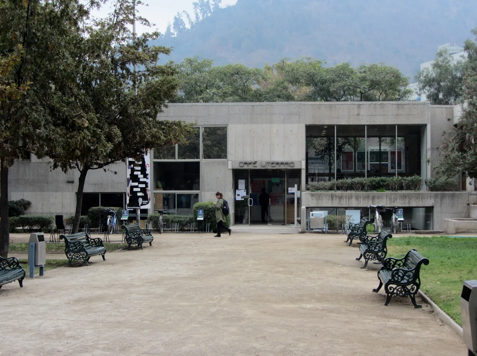 The low concrete and glass pavilion of the Café Literario in Parque Balmaceda, Santiago, with cast-iron benches along the path in front of it