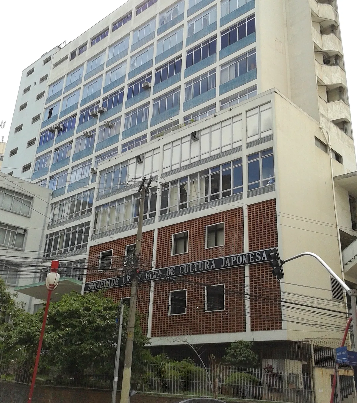 The Bunkyo building on Rua São Joaquim in São Paulo, a tall mid-century block with ribbon windows above a brick-faced lower storey carrying the Sociedade Brasileira de Cultura Japonesa sign