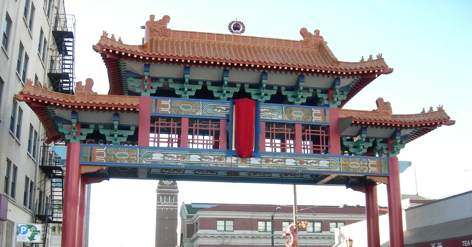 The Historic Chinatown Gate spanning South King Street in Seattle, a red and green ornamental arch with tiled roofs and a red lantern hung at its center